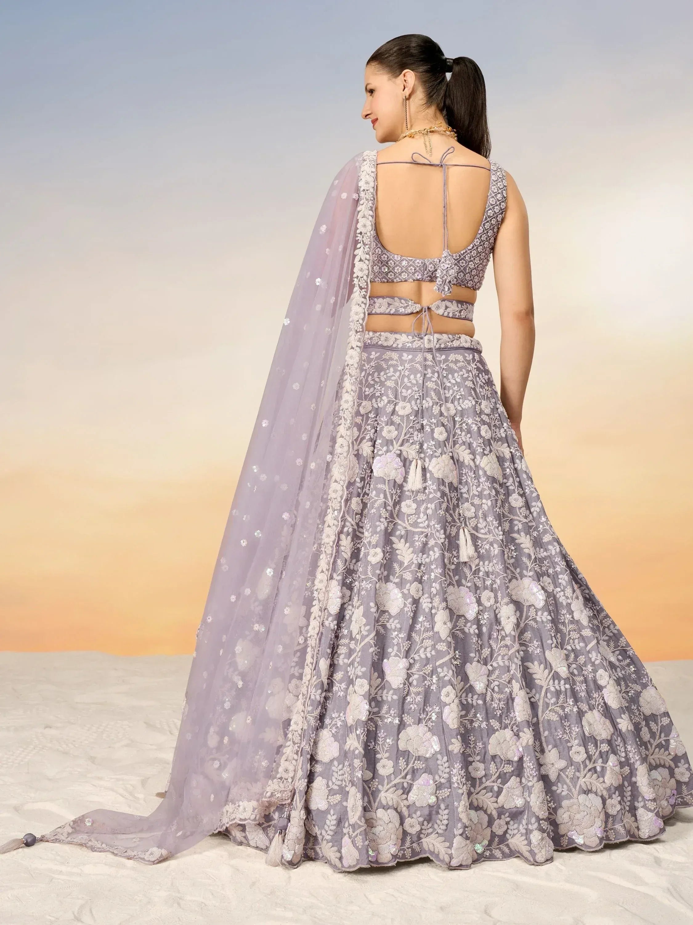 Lavender floral embroidered lehenga choli with backless blouse and sheer dupatta, ideal for Indian weddings and parties.