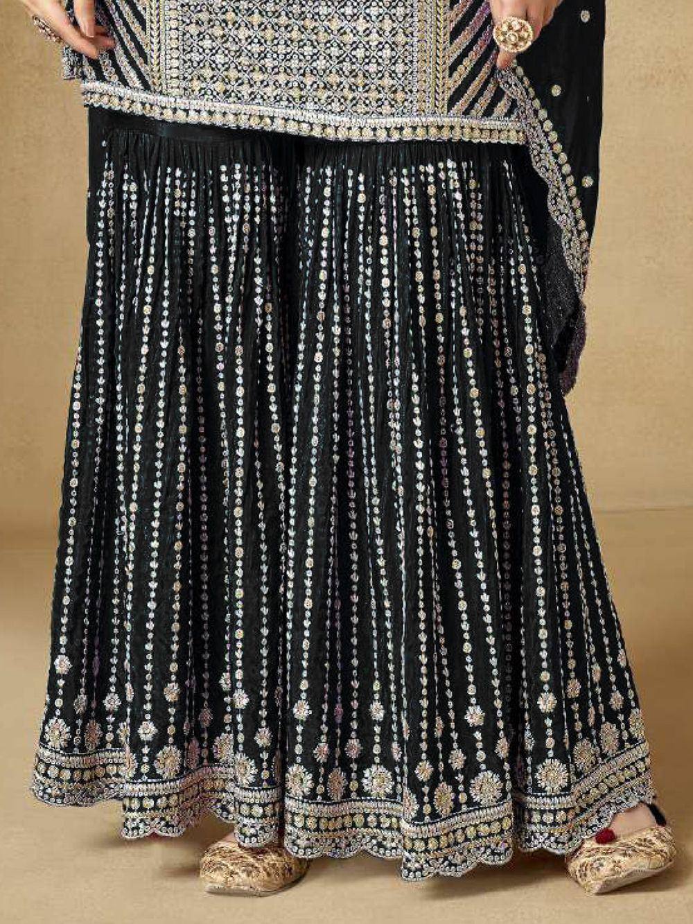 Black embroidered lehenga with intricate floral patterns and golden accents, paired with matching blouse and juttis.