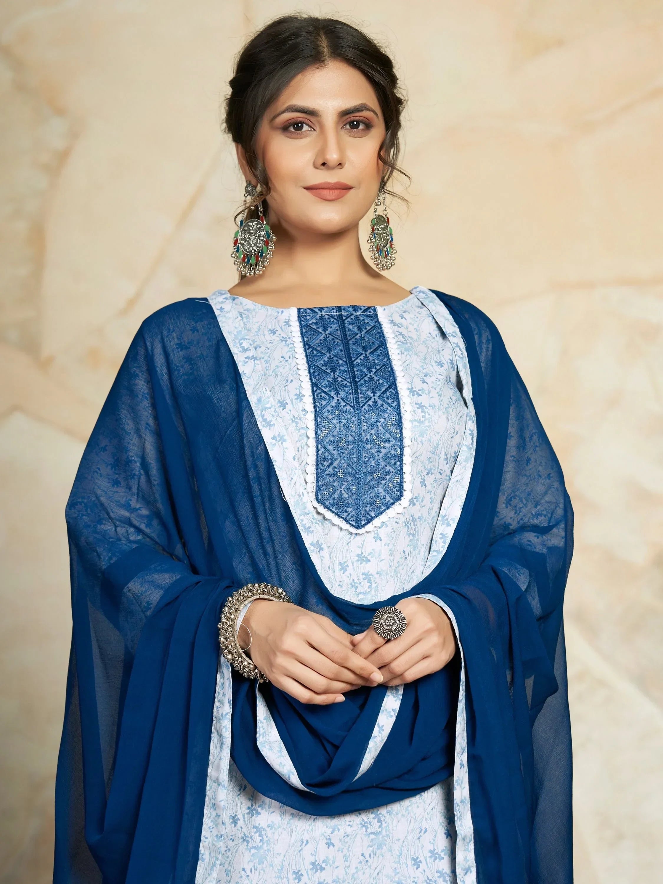 Woman in a blue and white salwar kameez with embroidered details and statement earrings
