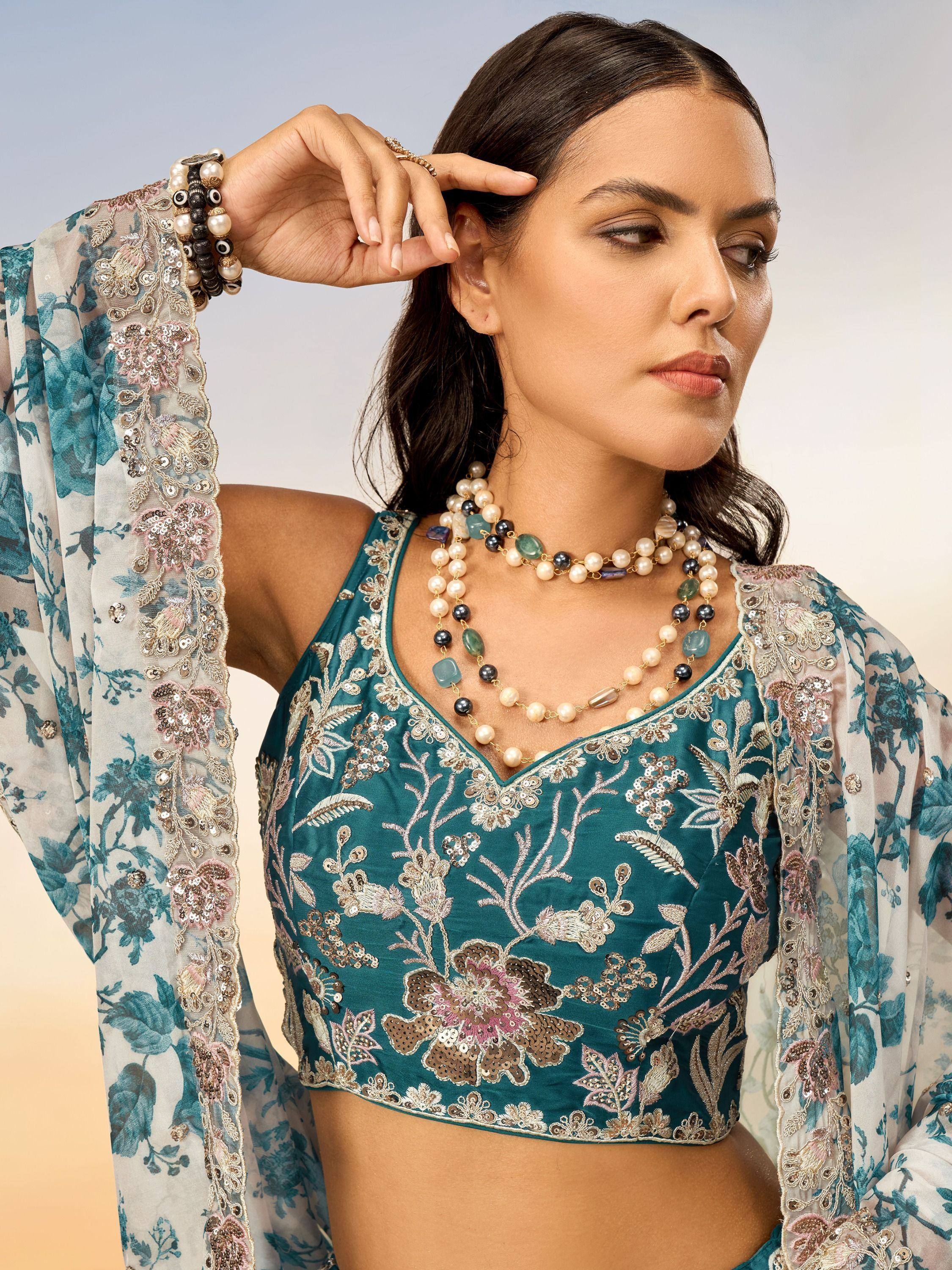 Teal embroidered blouse with floral dupatta, pearl necklace, and ethnic jewelry for Indian wear