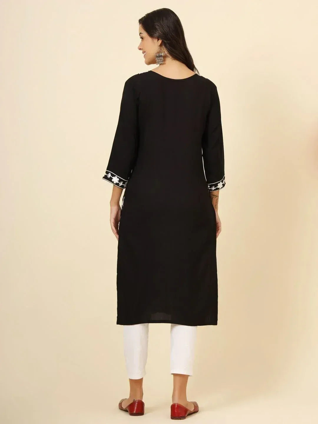 Black ethnic kurti with white floral embroidery on sleeves, paired with white pants and red flats