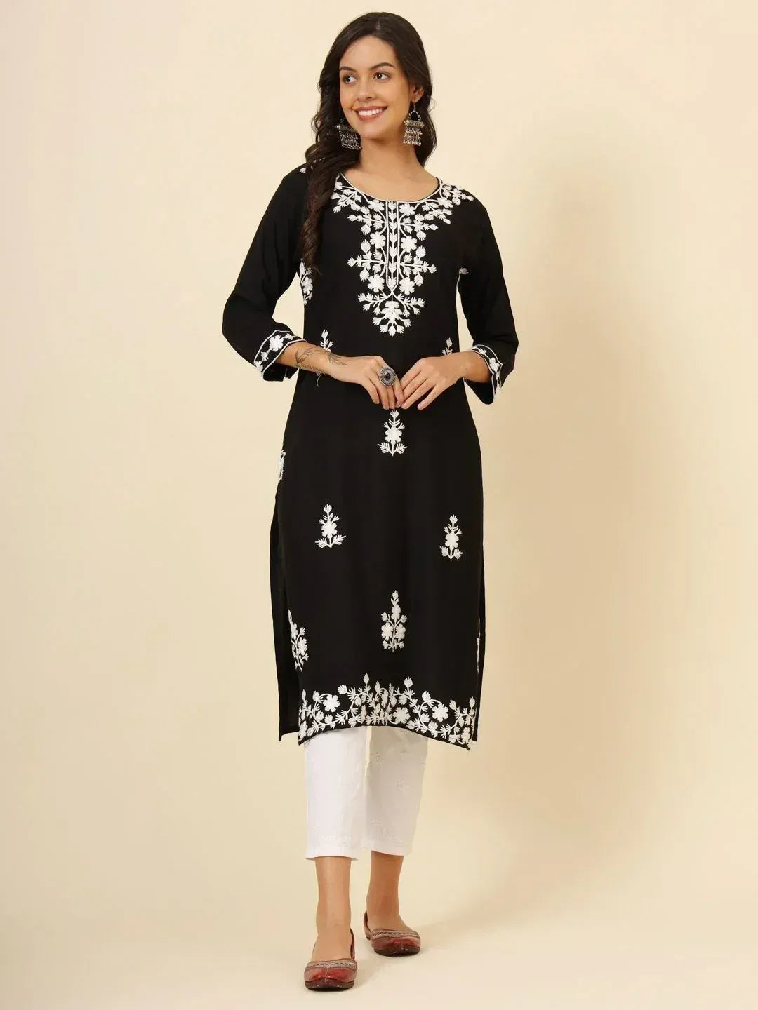 Black embroidered kurta with white floral patterns paired with white pants for ethnic wear