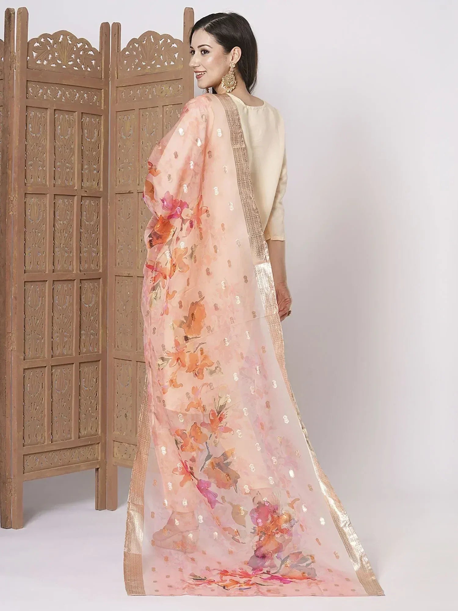 Woman in peach floral printed saree with gold border, ethnic Indian wear