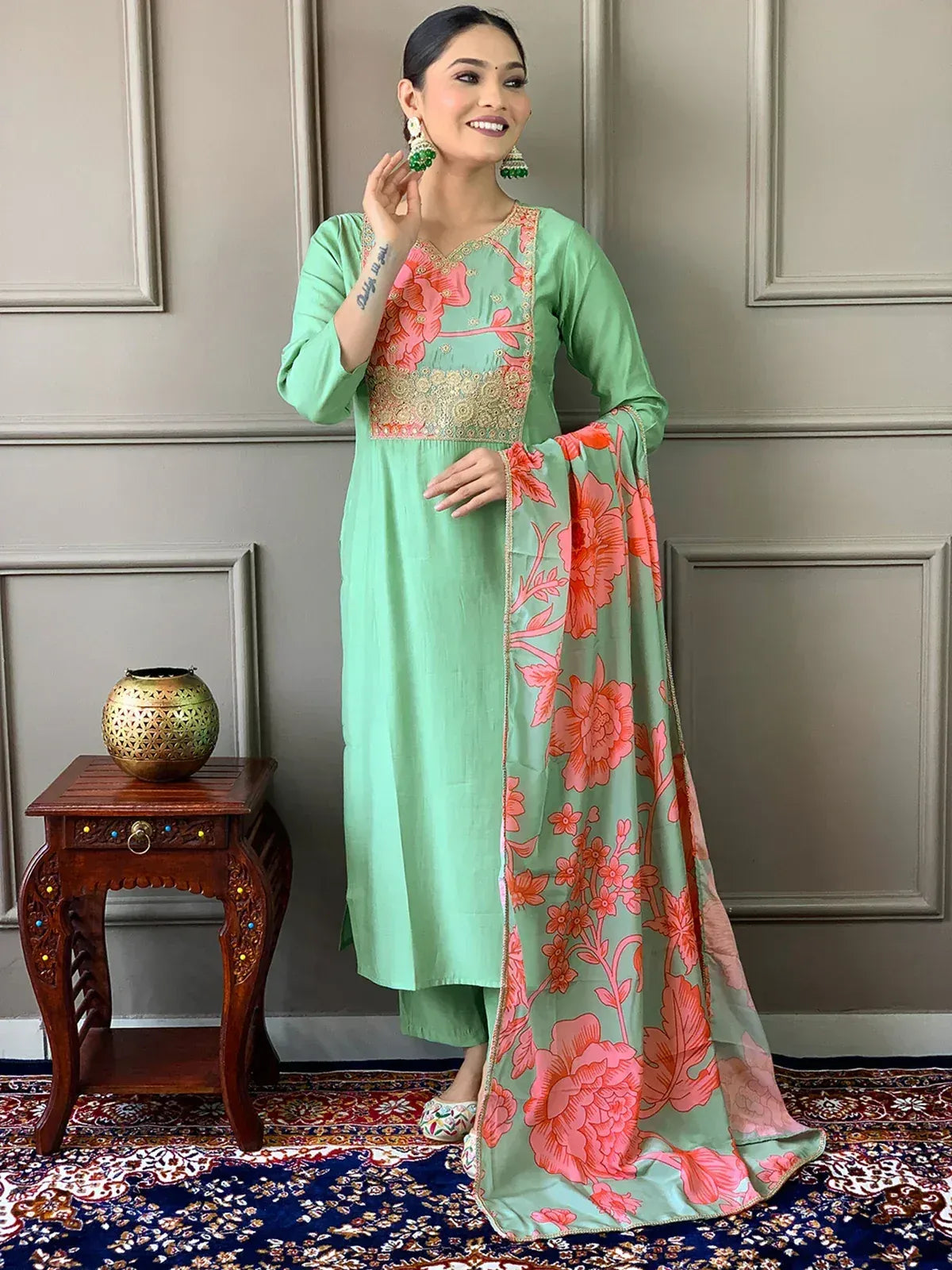Mint green salwar kameez with pink floral print and gold embroidery, paired with matching dupatta and ethnic jewelry.