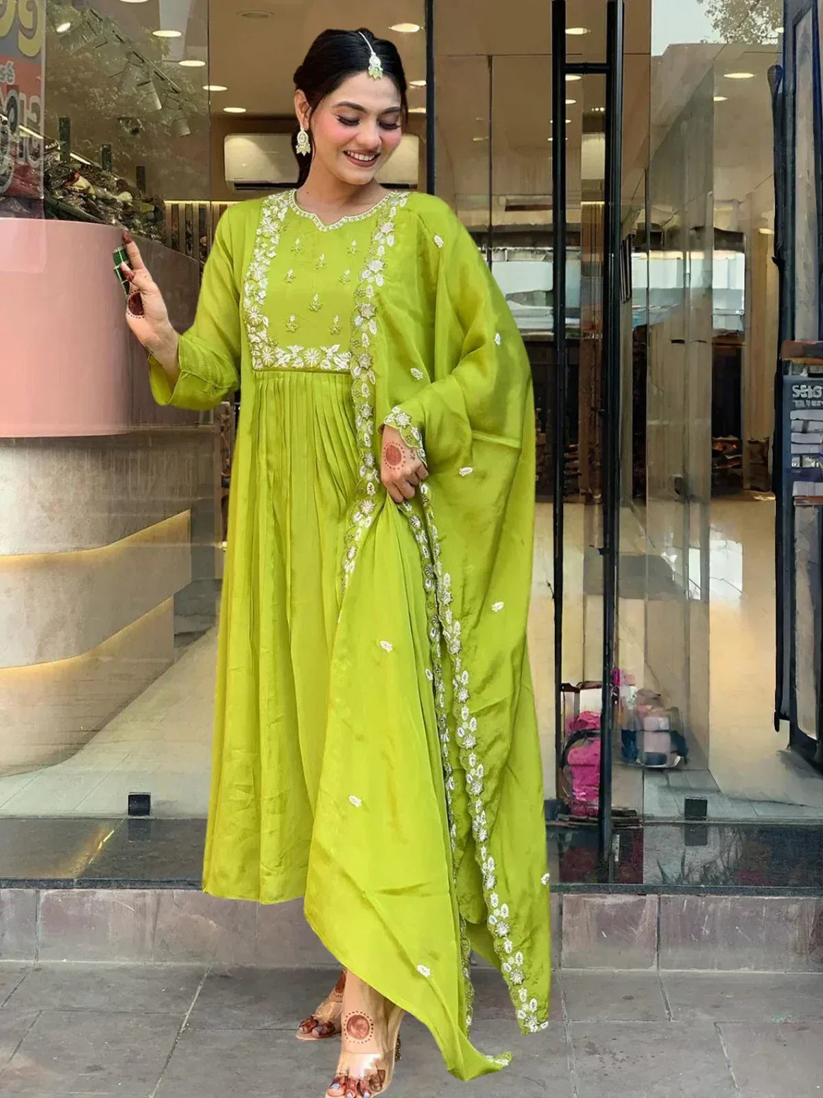 Woman in vibrant green embroidered anarkali suit with floral detailing, perfect for ethnic occasions