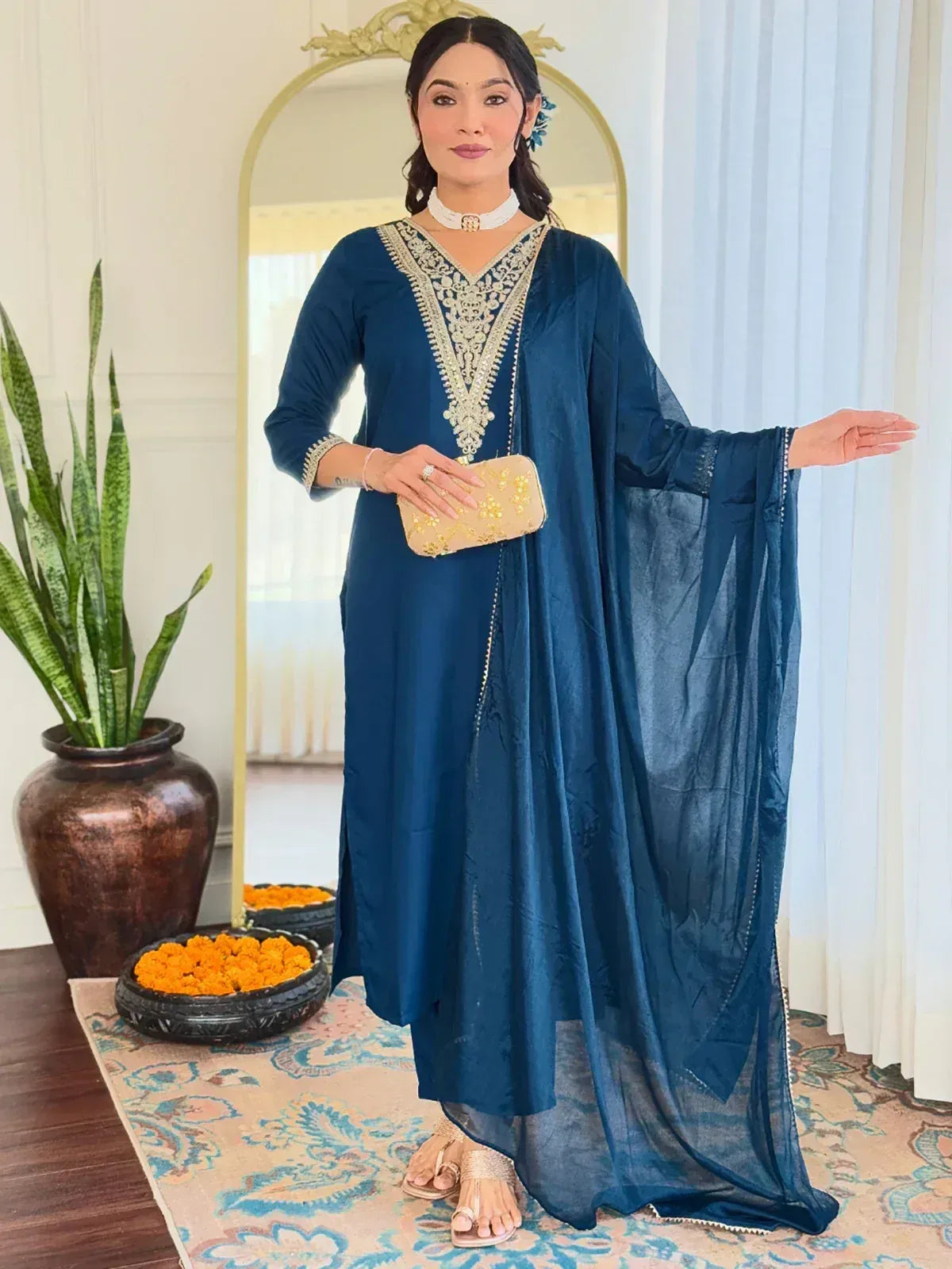 Elegant blue ethnic gown with gold embroidery, paired with matching dupatta and clutch for festive occasions