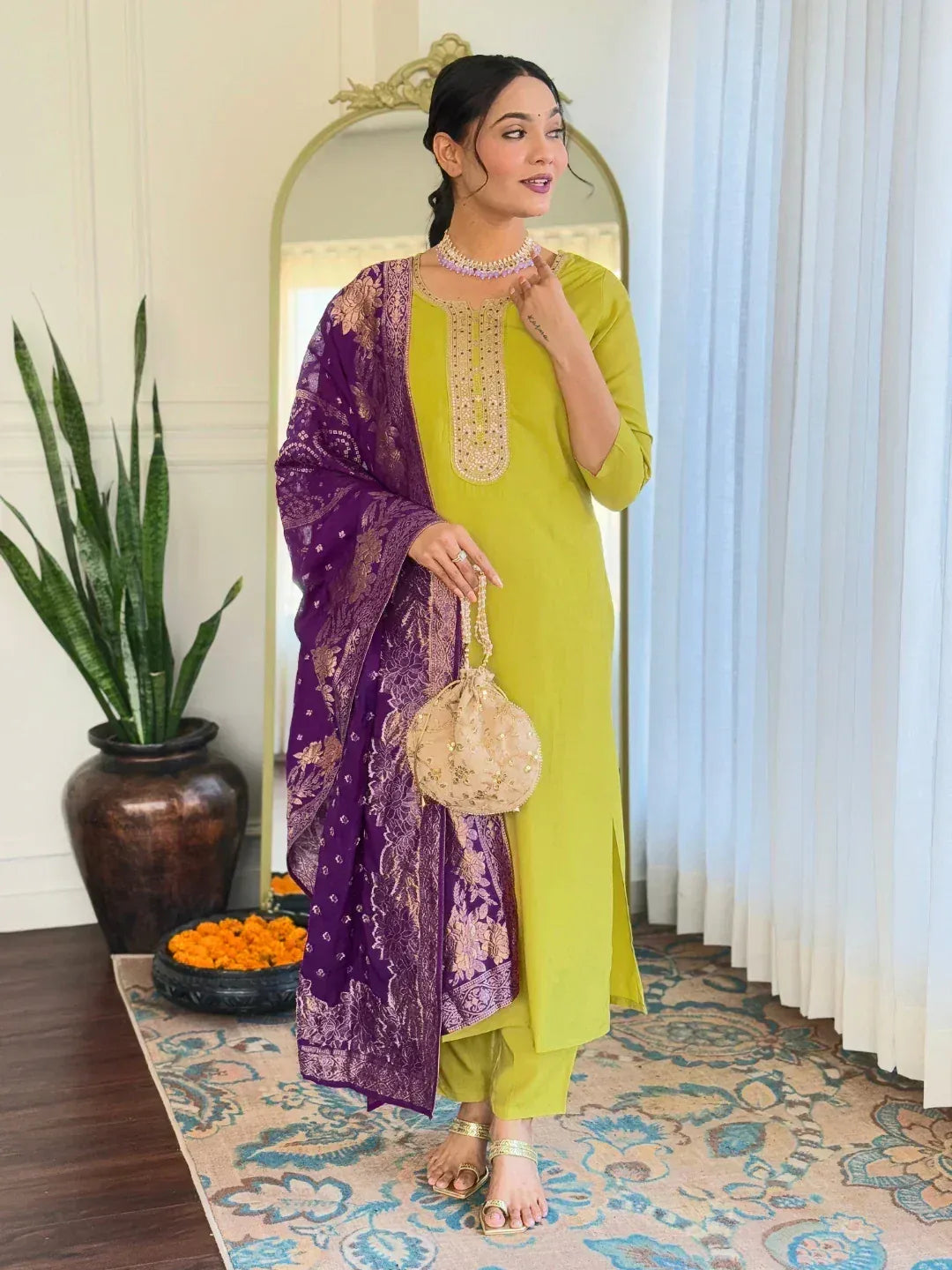 Woman in green kurta with purple embroidered dupatta, gold jewelry, and ethnic accessories