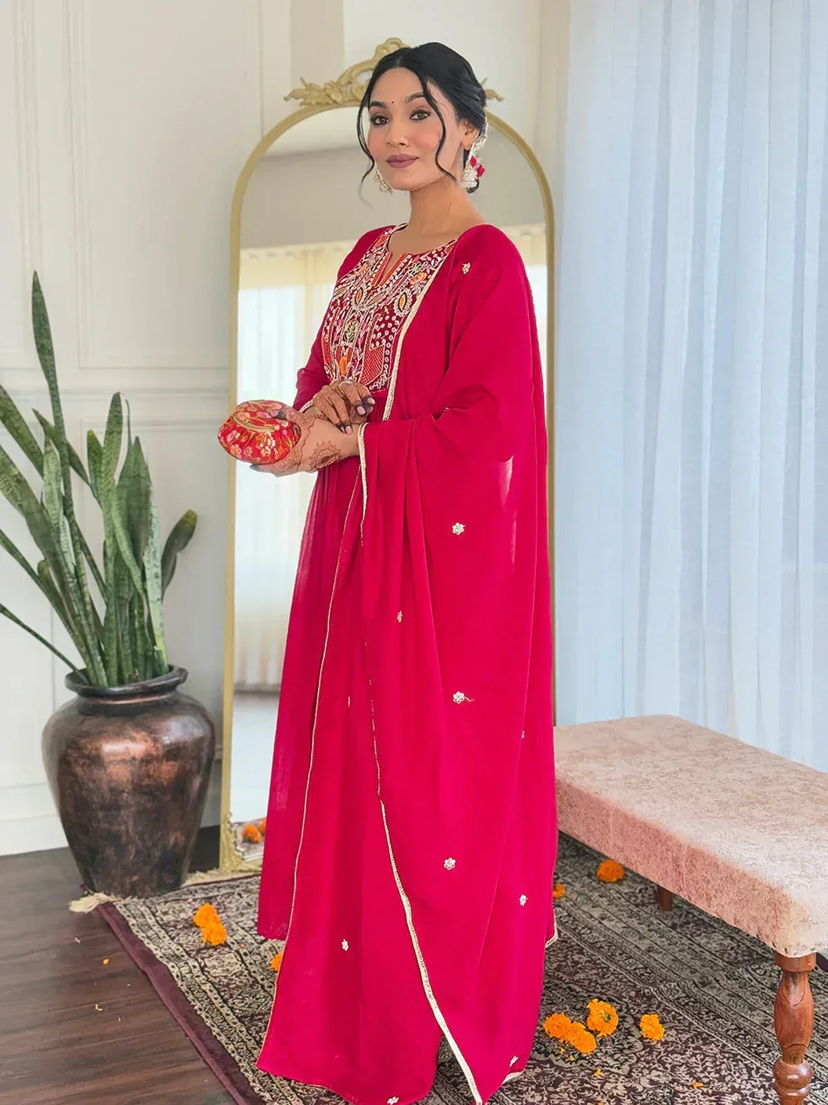 Woman in vibrant red ethnic gown with intricate embroidery, perfect for Indian celebrations and festive occasions.