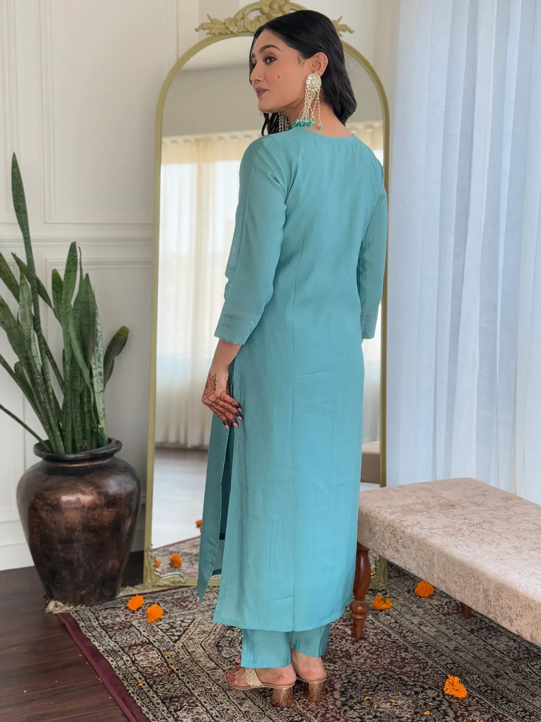 Woman in turquoise Indian ethnic kurta set with henna, mirror, and marigolds