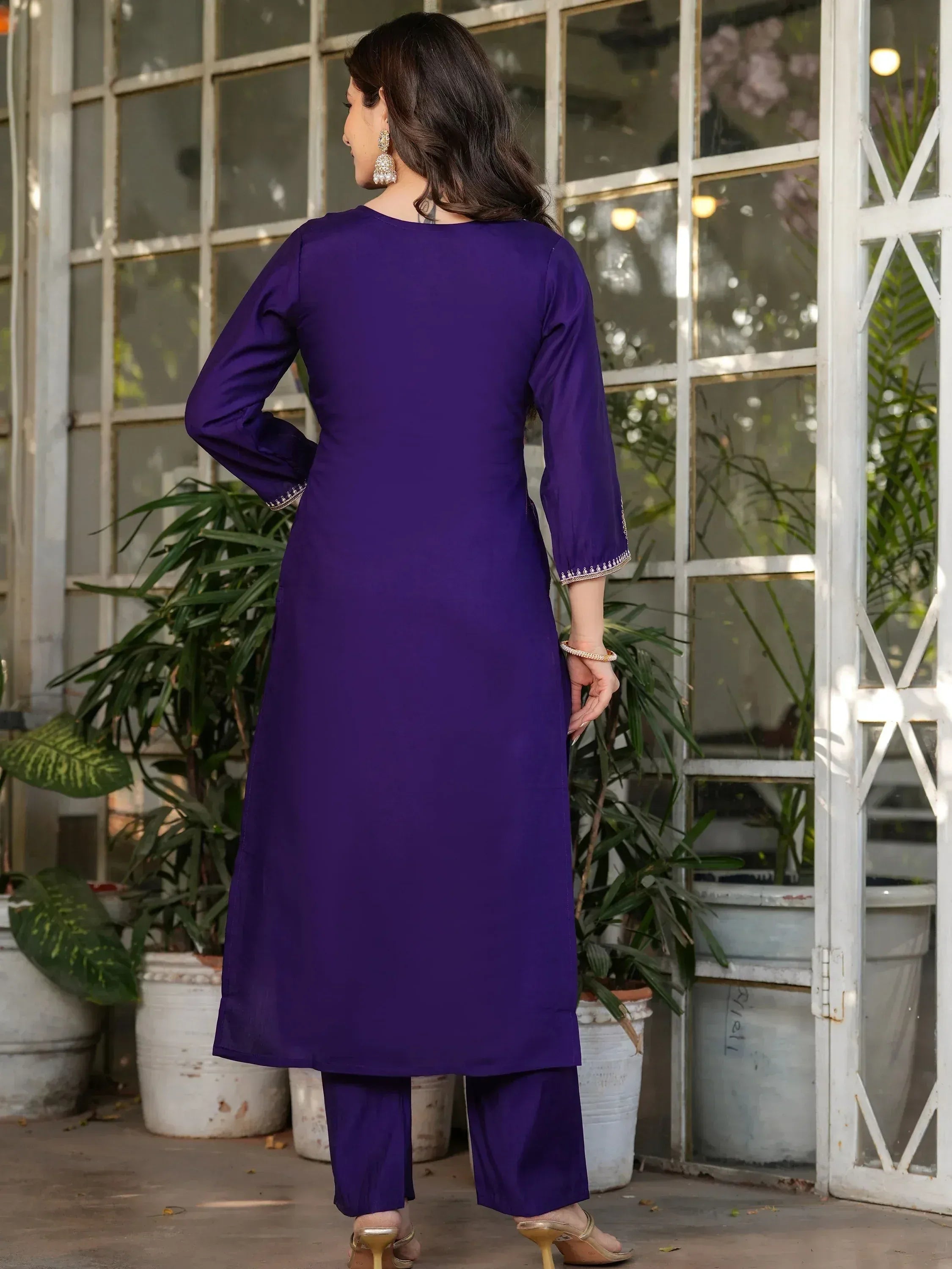 Purple ethnic kurta with matching pants, long sleeves, and delicate embroidery, styled with gold heels and jhumka earrings.