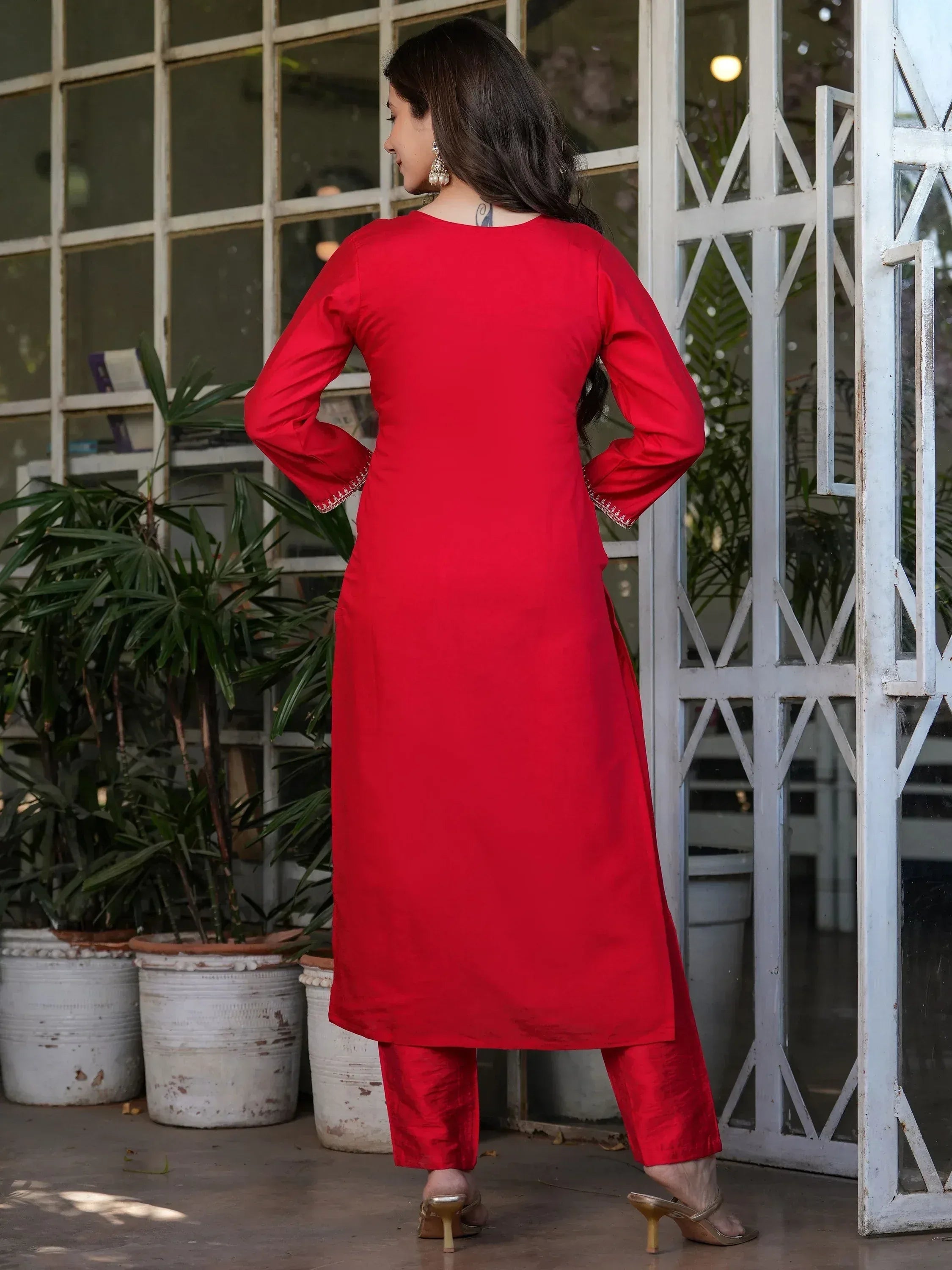 Red ethnic kurti with matching pants, long sleeves, and side slits, styled with gold heels and jhumka earrings.