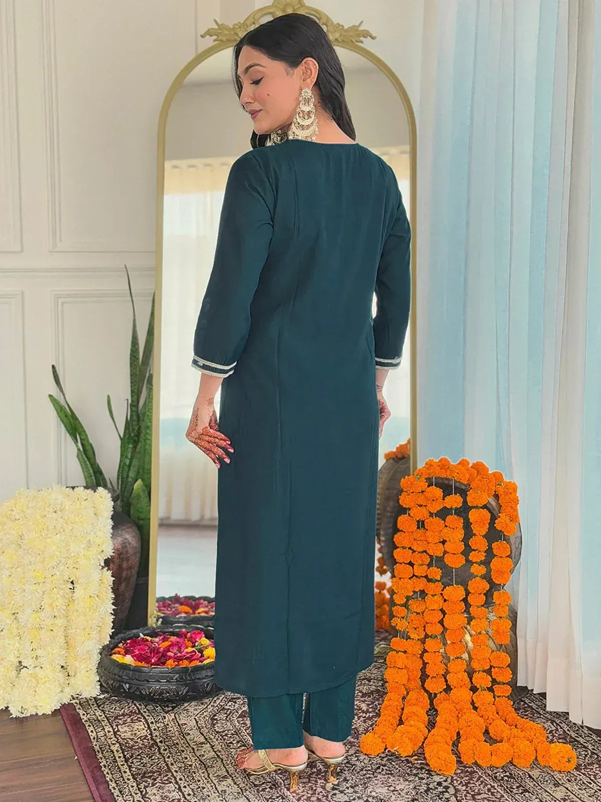 Teal ethnic kurta with contrast trim, paired with matching pants, styled with jhumka earrings and floral decor