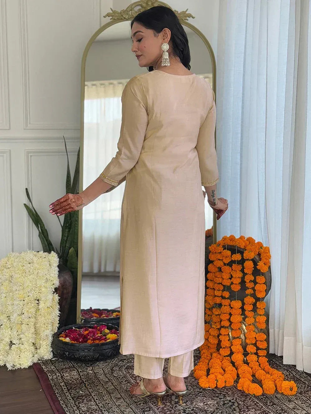 Beige ethnic kurta with matching pants, henna hands, and floral decor for Indian occasions