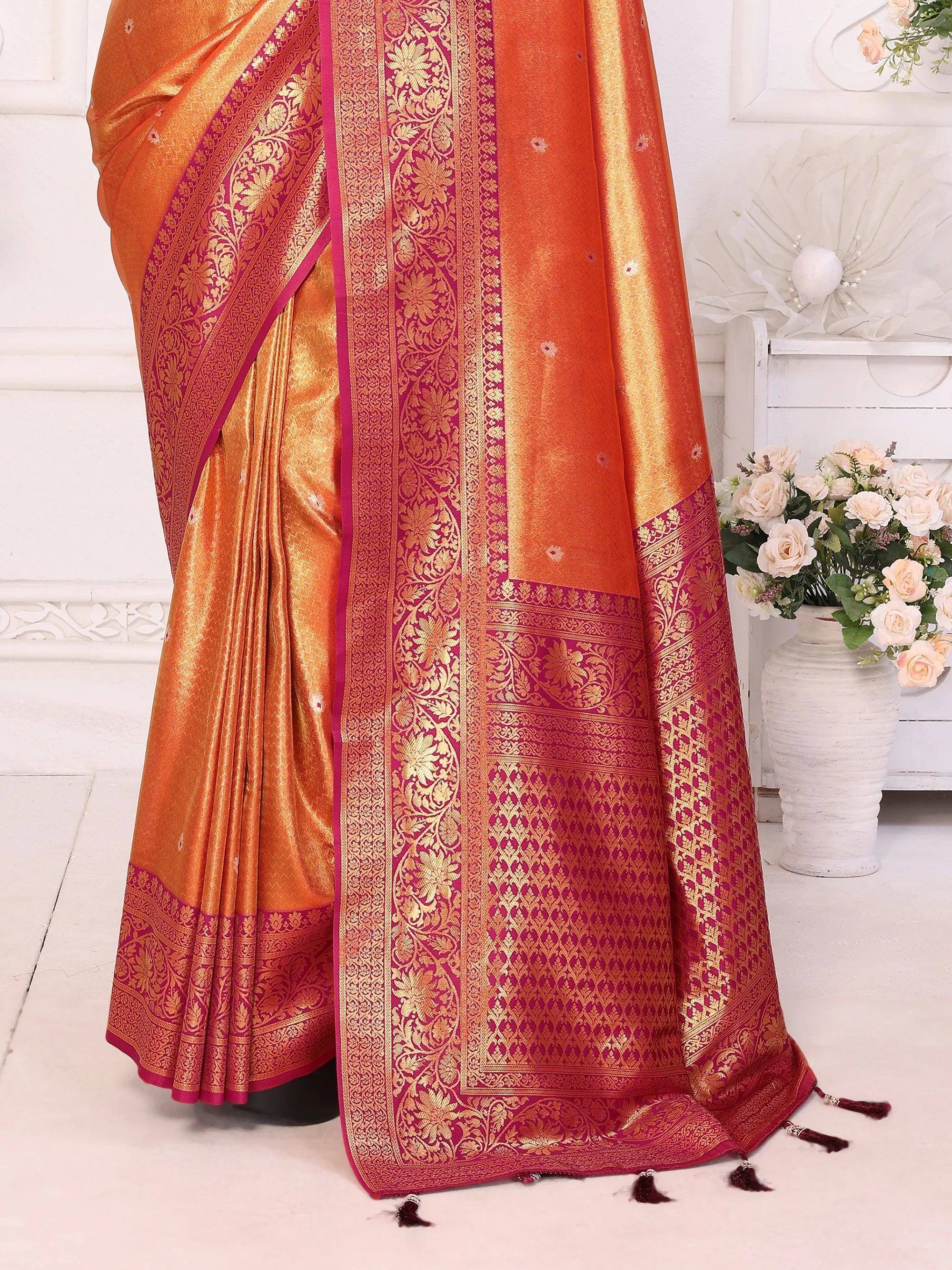 Orange and pink designer saree with gold floral embroidery and tassels, perfect for ethnic wear.