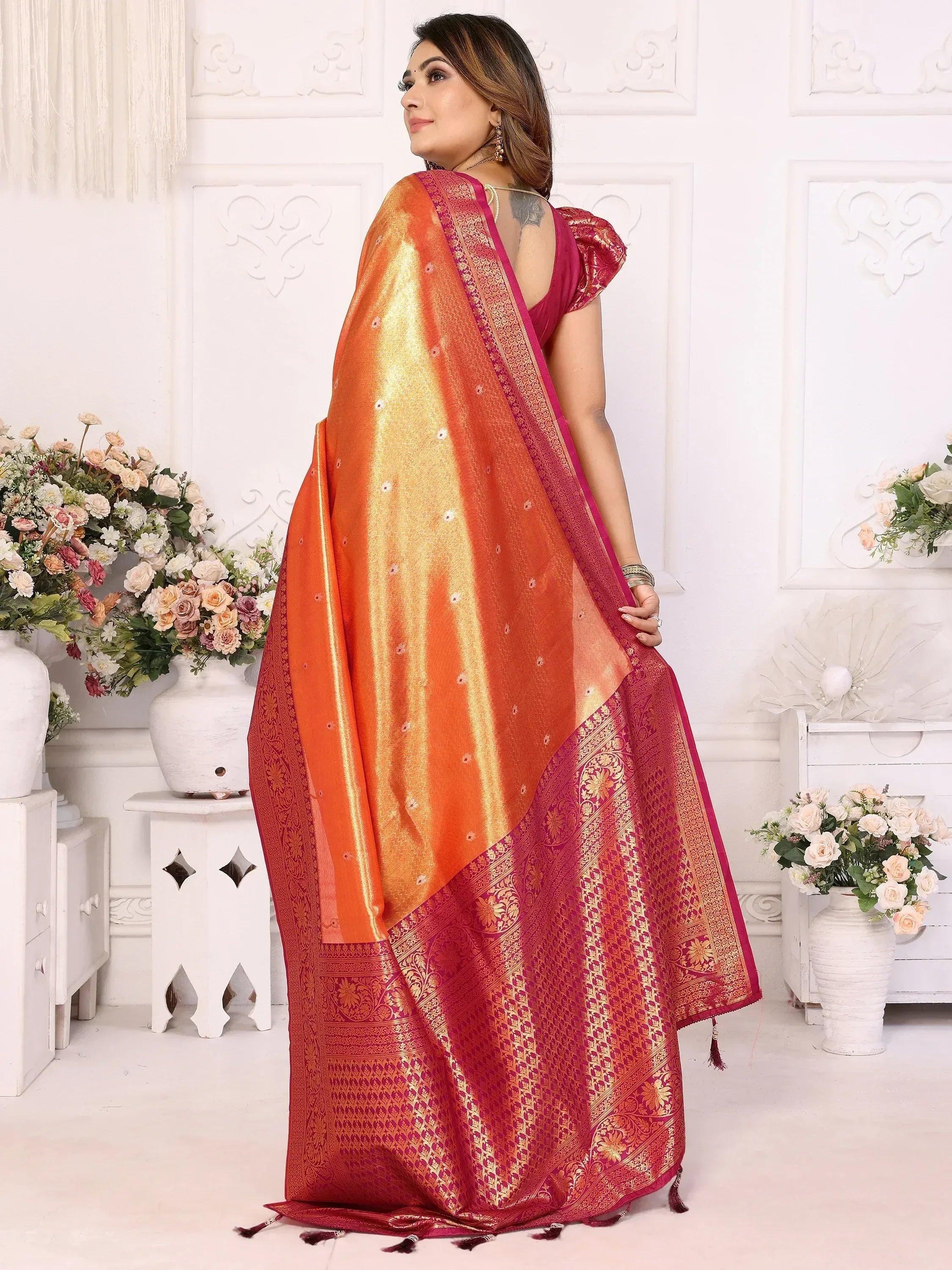 Orange and maroon designer saree with gold embroidery and tassels, perfect for ethnic occasions.