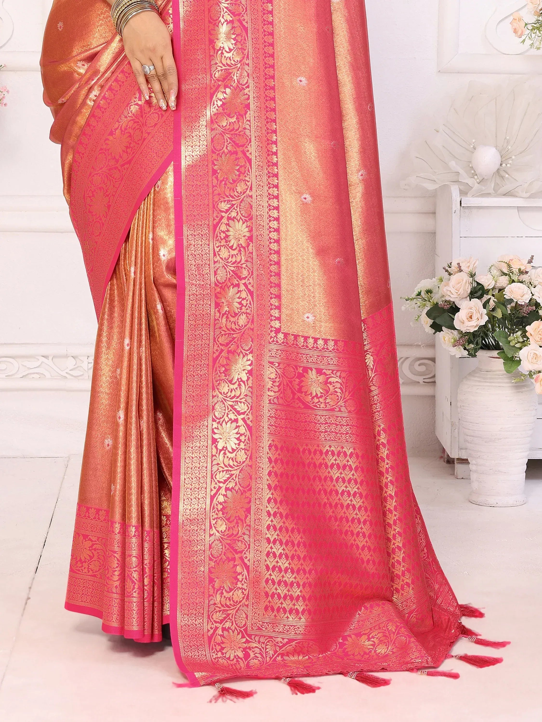 Elegant pink and gold embroidered saree with intricate floral patterns and tassels