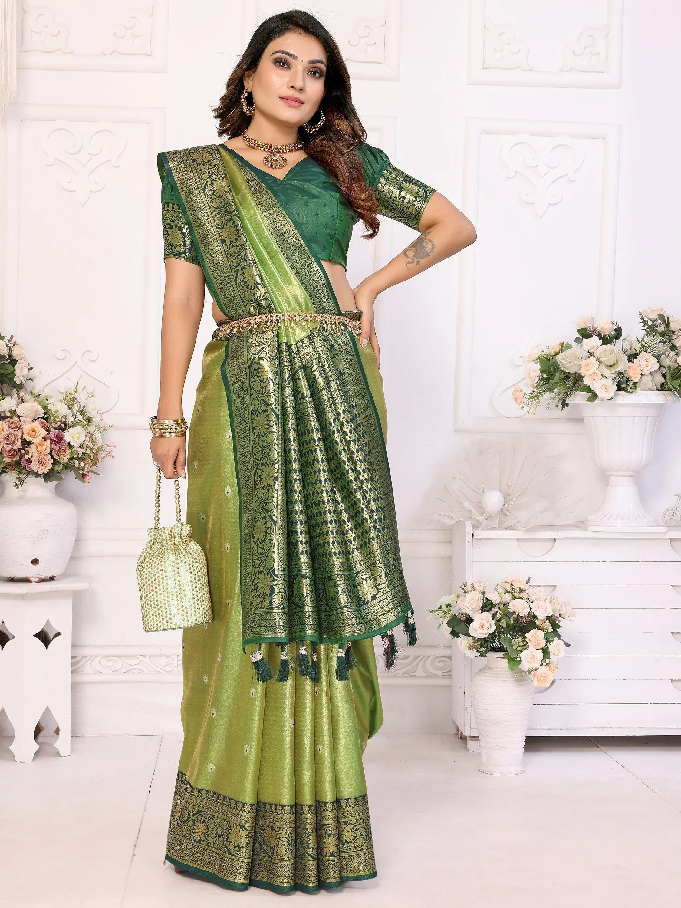 Green designer saree with gold embroidery and tassels, paired with matching blouse and potli bag