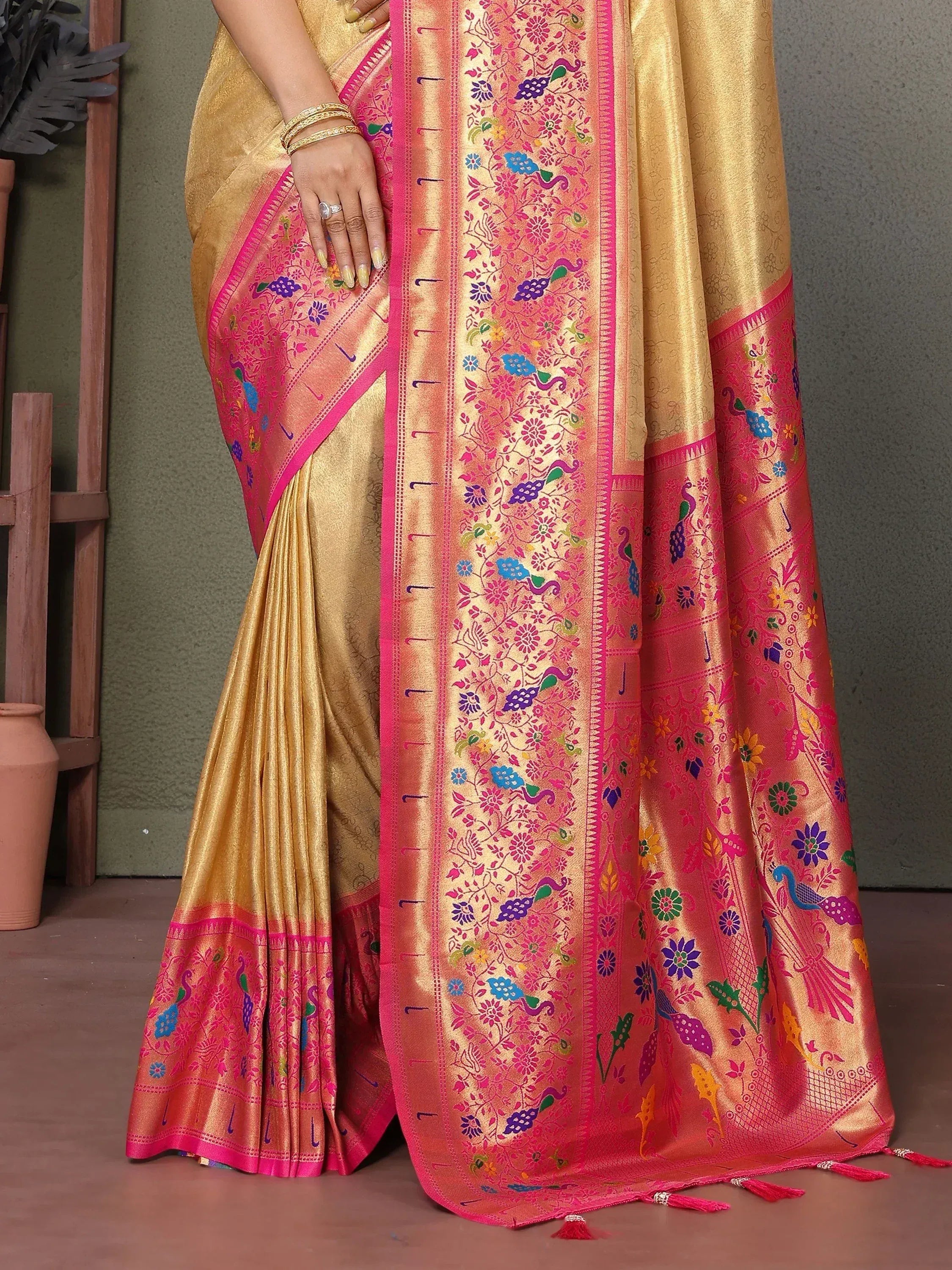 Golden saree with vibrant pink border and peacock floral embroidery, perfect for ethnic occasions.