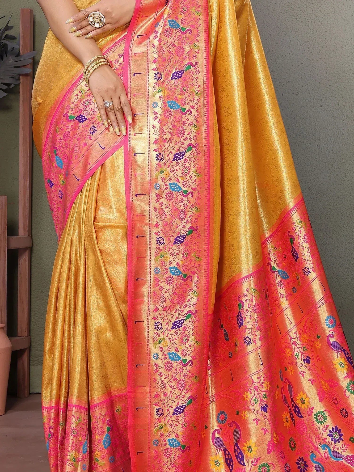 Golden saree with vibrant pink border, peacock and floral motifs, perfect for ethnic wear.
