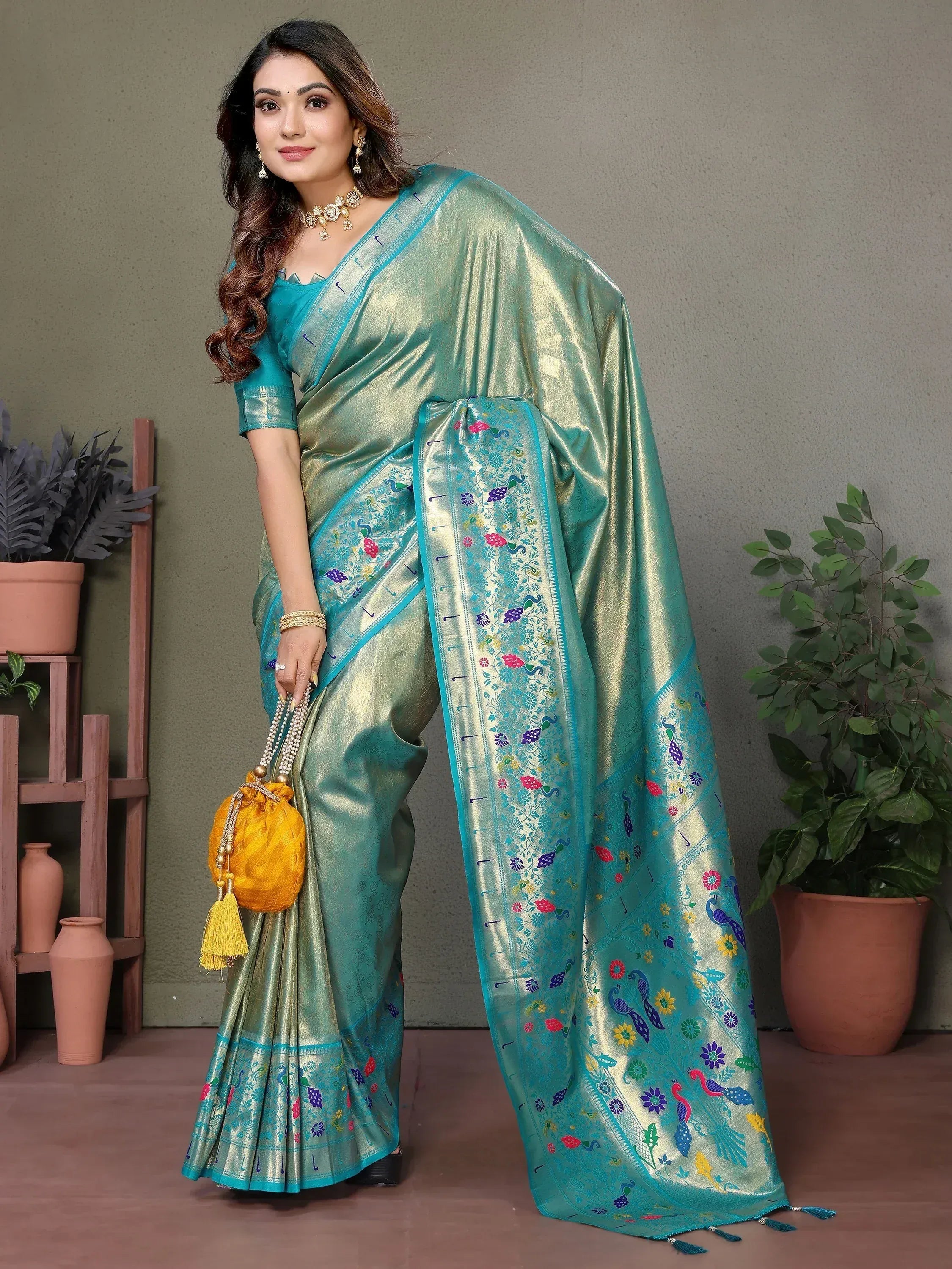 Elegant teal saree with peacock embroidery, paired with matching blouse and gold accessories for festive occasions.