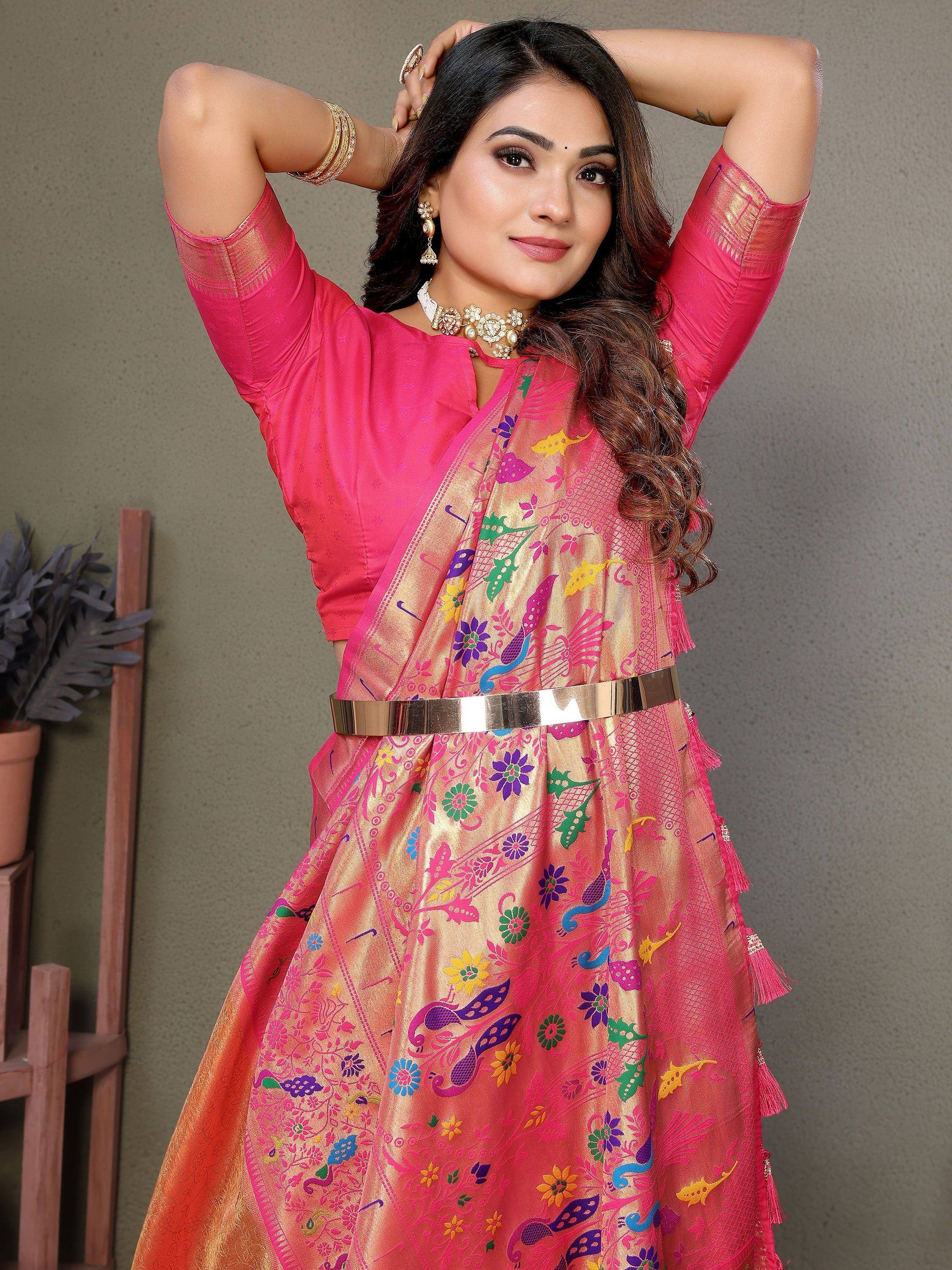 Vibrant pink ethnic gown with colorful floral and peacock embroidery, styled with a metallic belt and traditional jewelry.