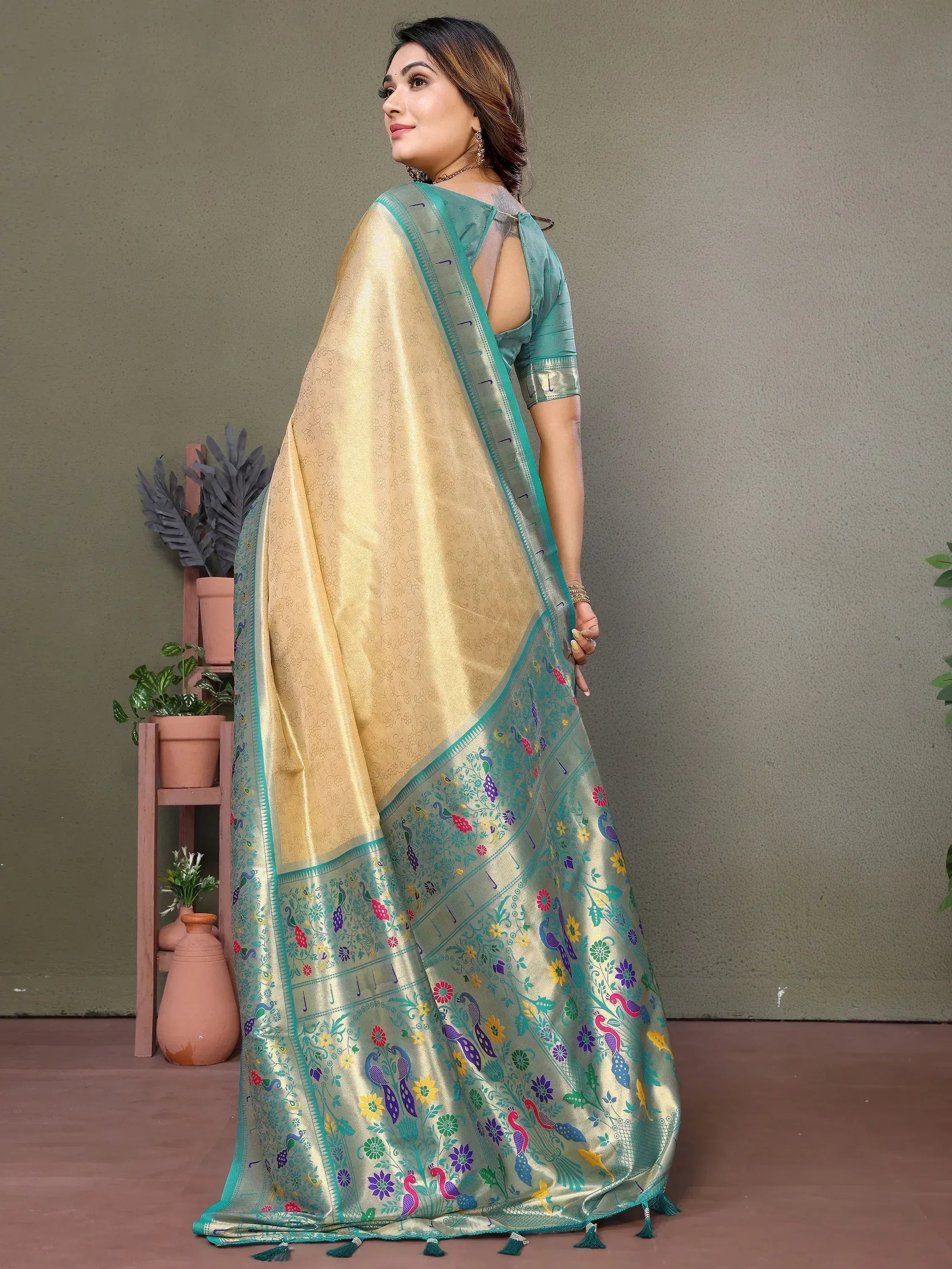 Elegant golden saree with peacock and floral embroidery, paired with a teal blouse for festive occasions.