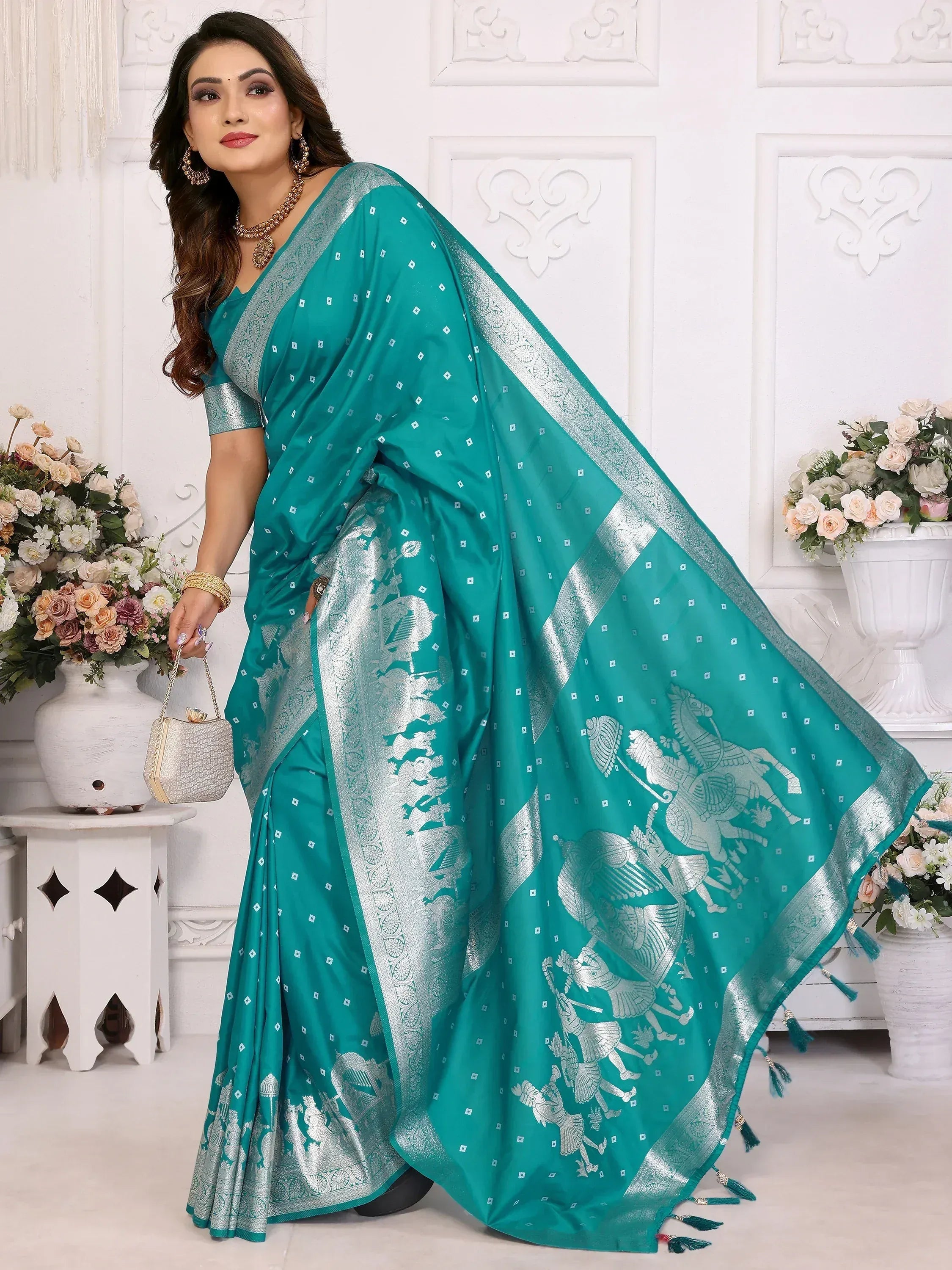 Teal saree with silver horse motifs and border, styled with ethnic jewelry and clutch