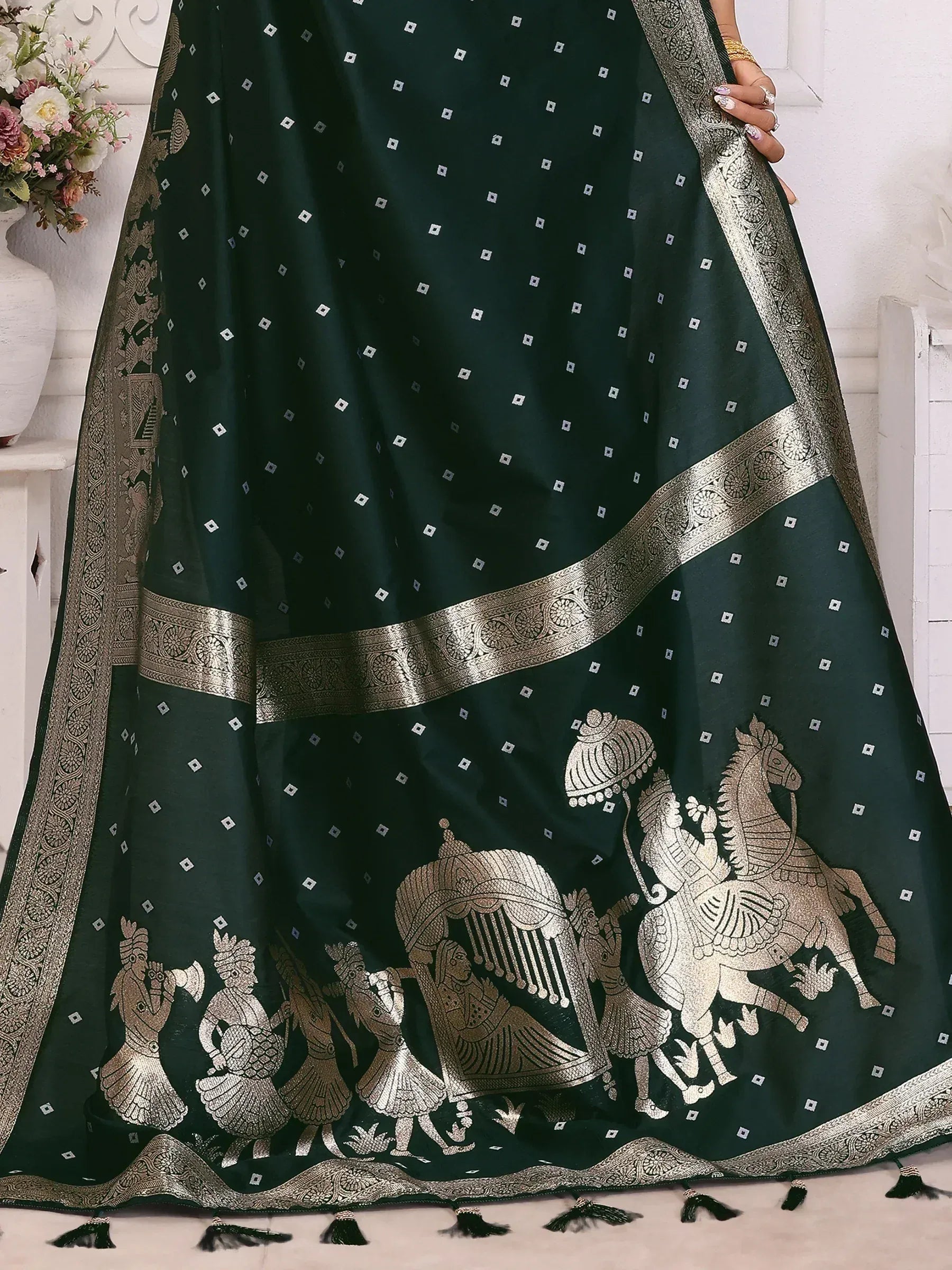 Dark green ethnic saree with gold warrior and horse motifs, intricate border, and tassels