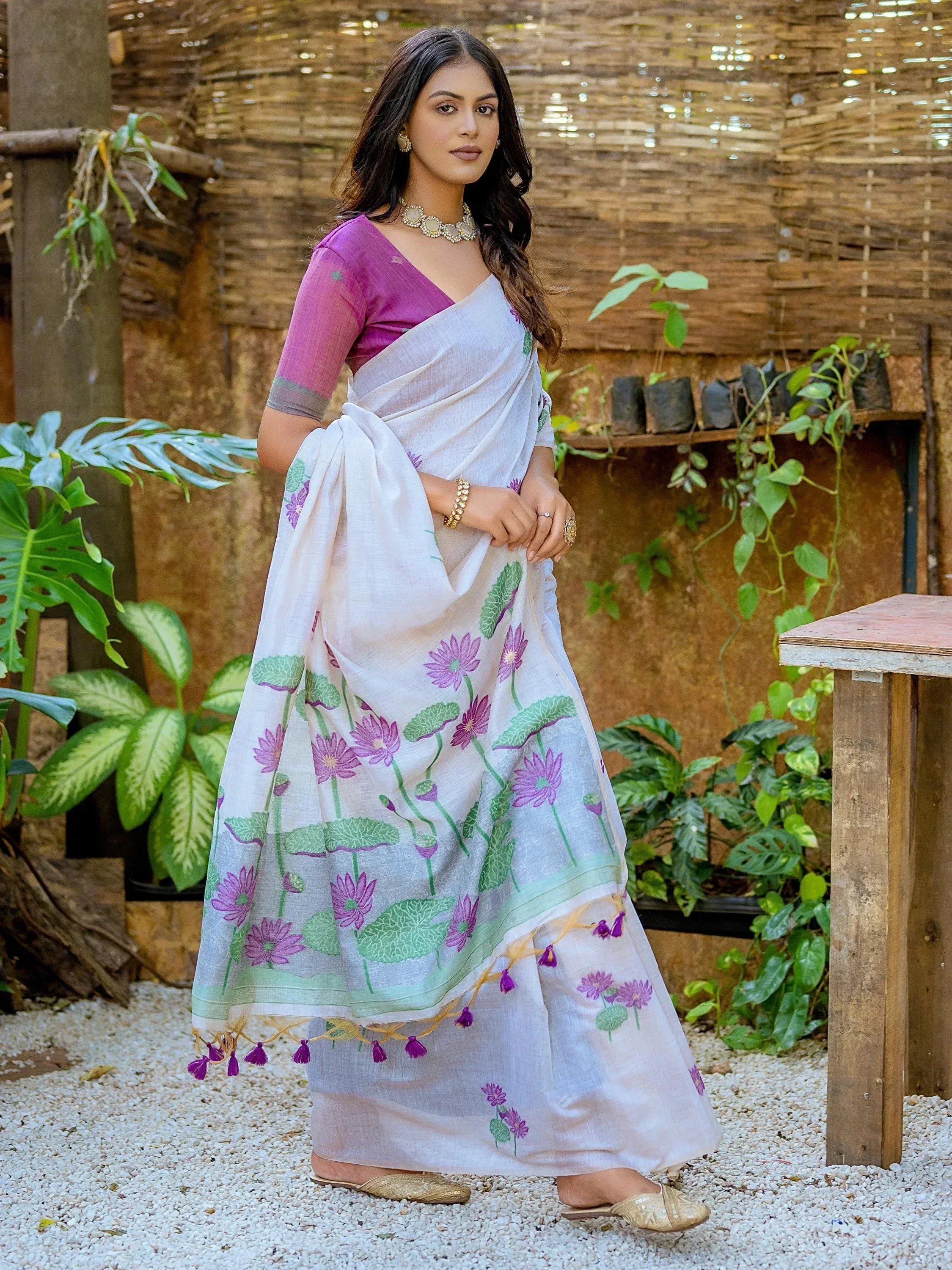 White saree with purple floral print, paired with a purple blouse, ideal for ethnic wear occasions.