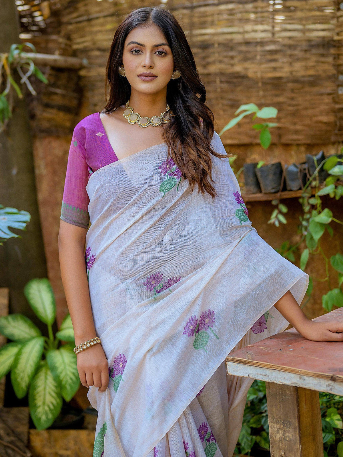 Elegant white saree with purple floral embroidery, paired with a vibrant pink blouse, perfect for ethnic occasions.