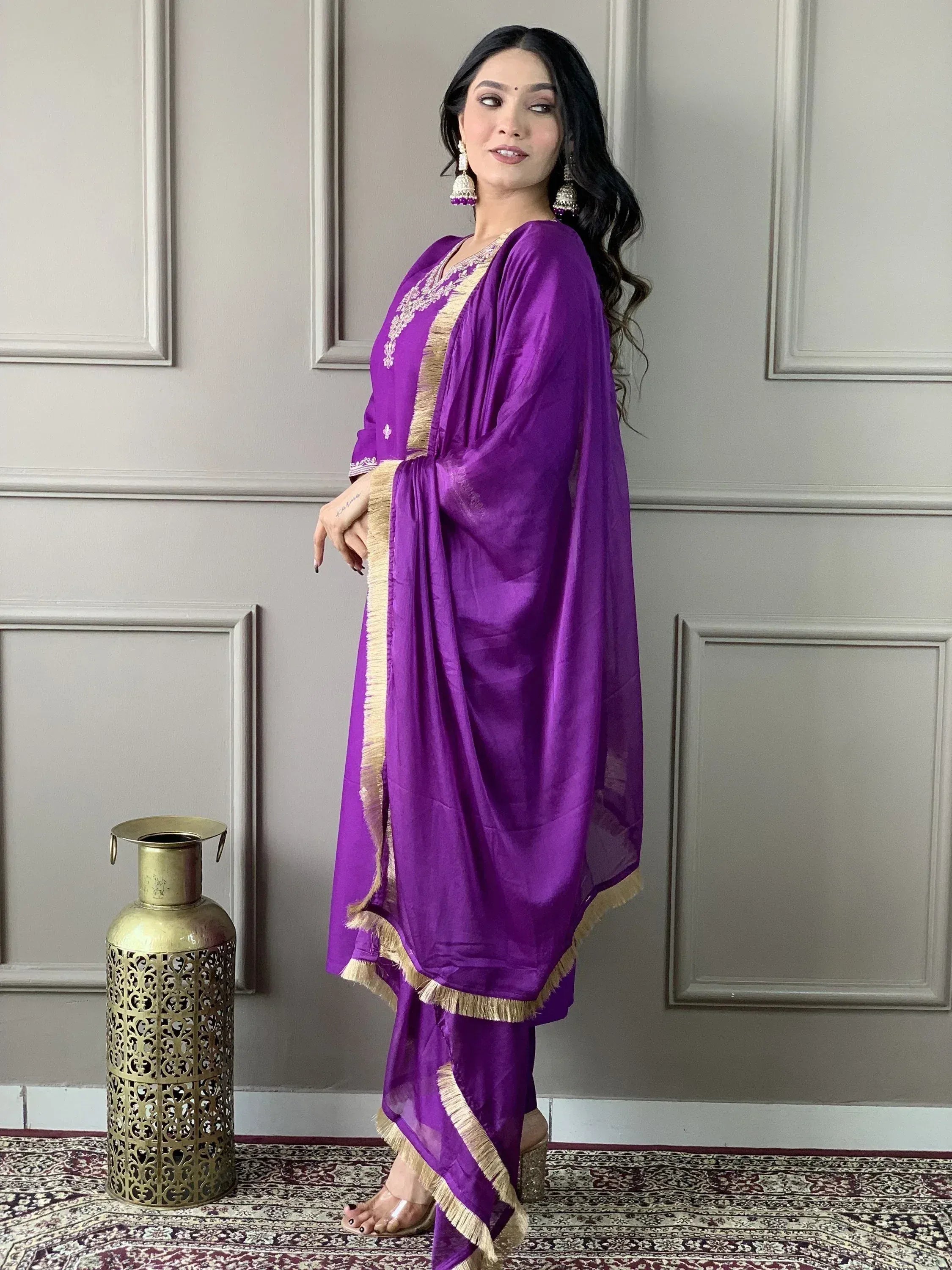 Purple ethnic salwar kameez with gold trim and fringe, styled with statement earrings for festive occasions.