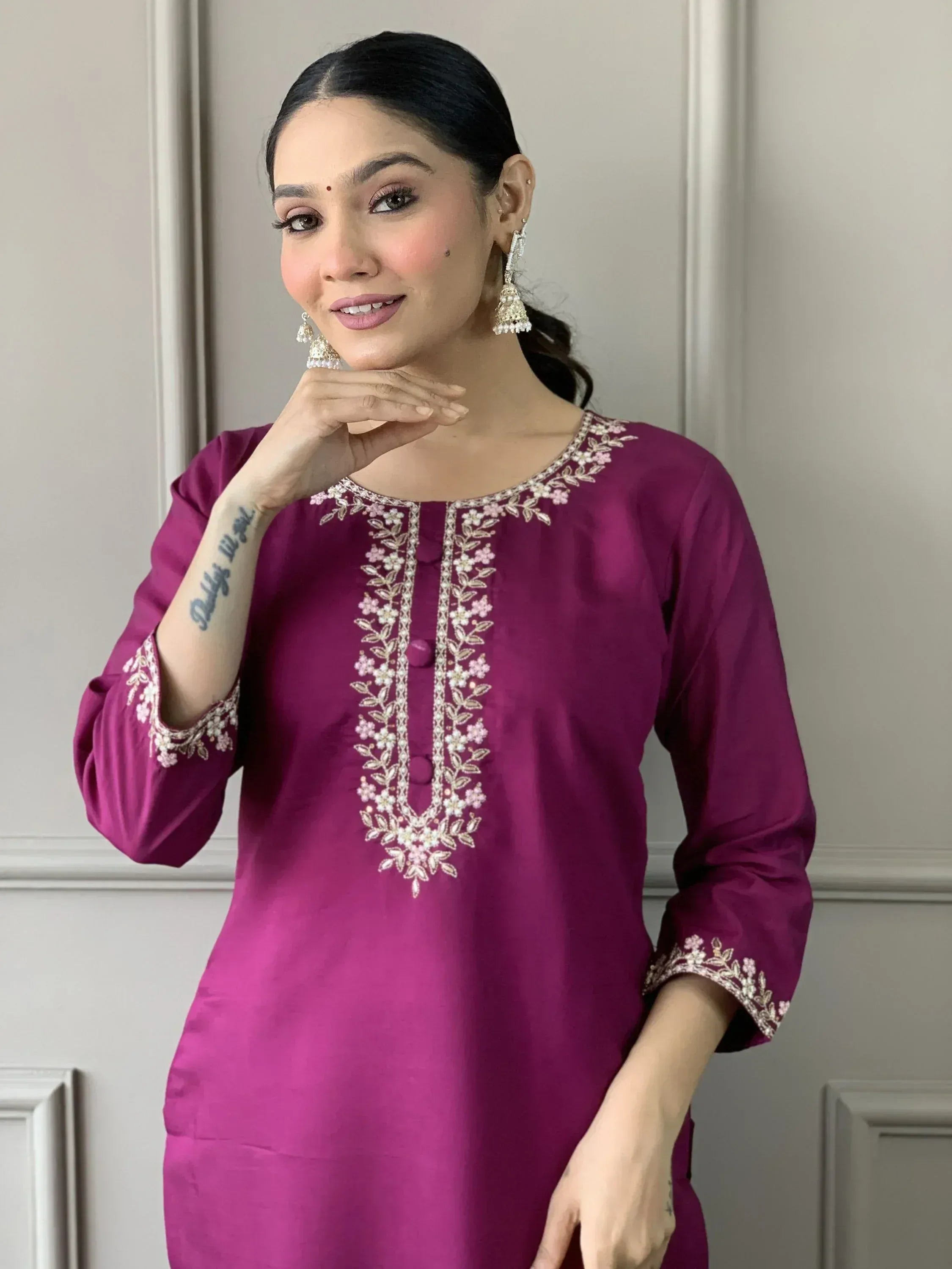 Purple embroidered kurta with floral neckline and sleeve details, paired with jhumka earrings