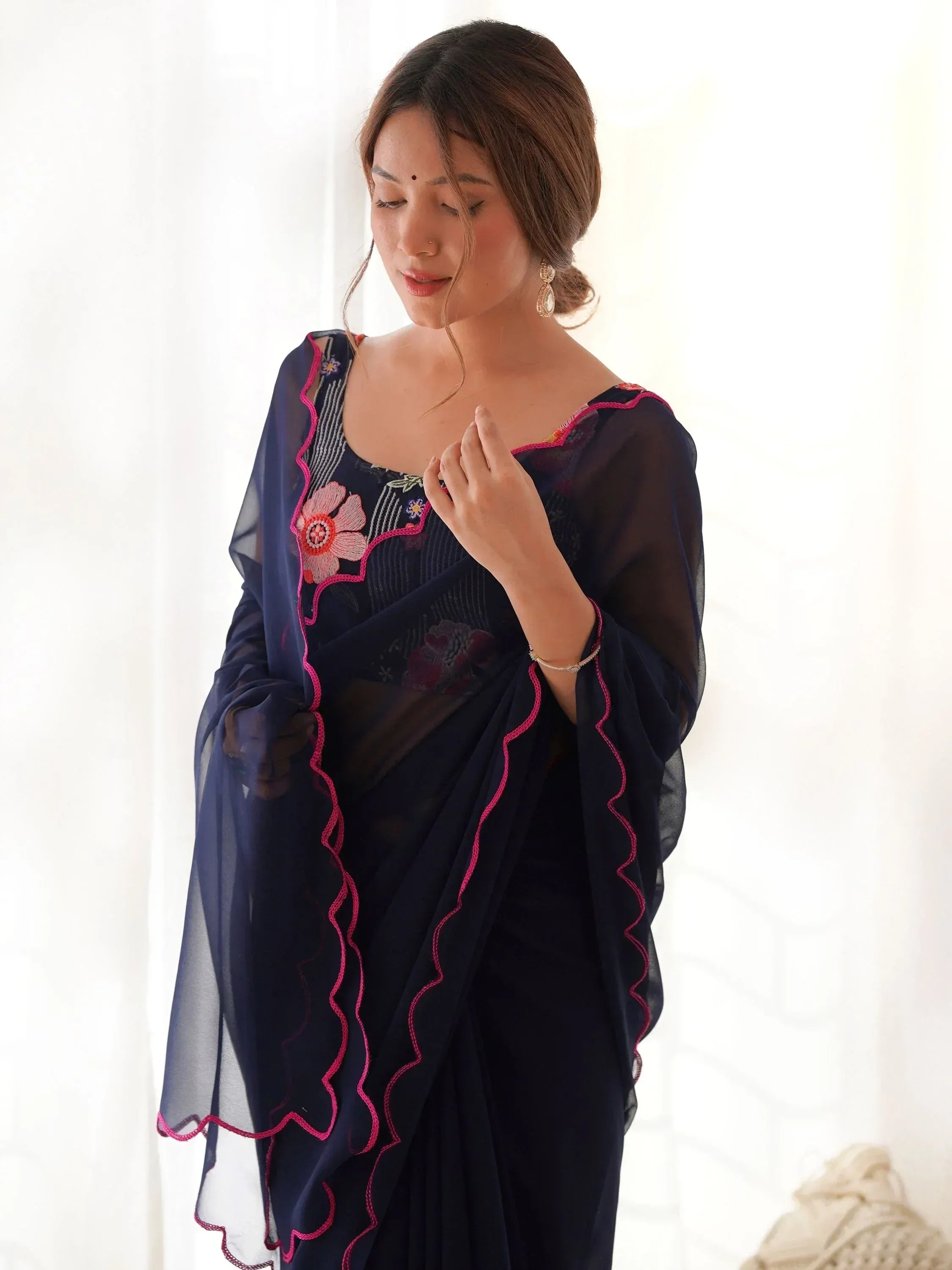 Navy blue ethnic saree with pink floral embroidery and ruffled border, perfect for Indian occasions