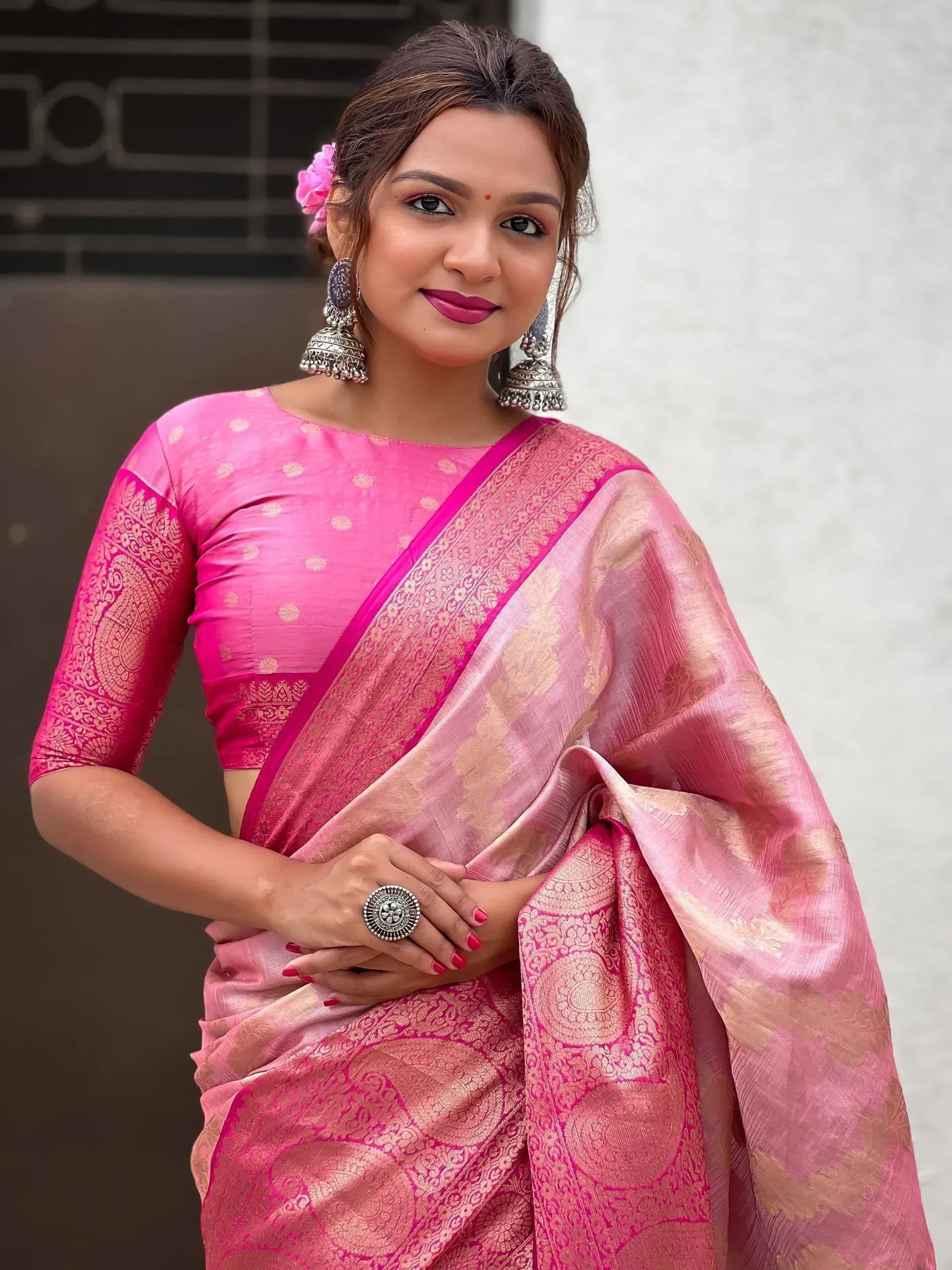 Pink designer saree with gold embroidery, paired with matching blouse and jhumka earrings for ethnic wear