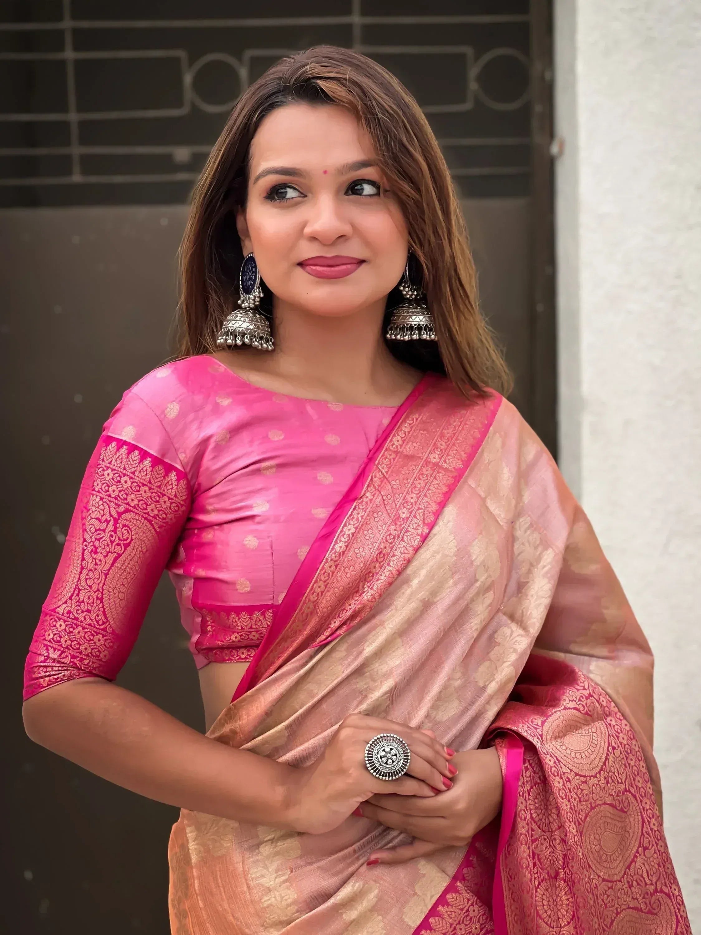 Woman in pink and gold designer saree with embroidered blouse and jhumka earrings