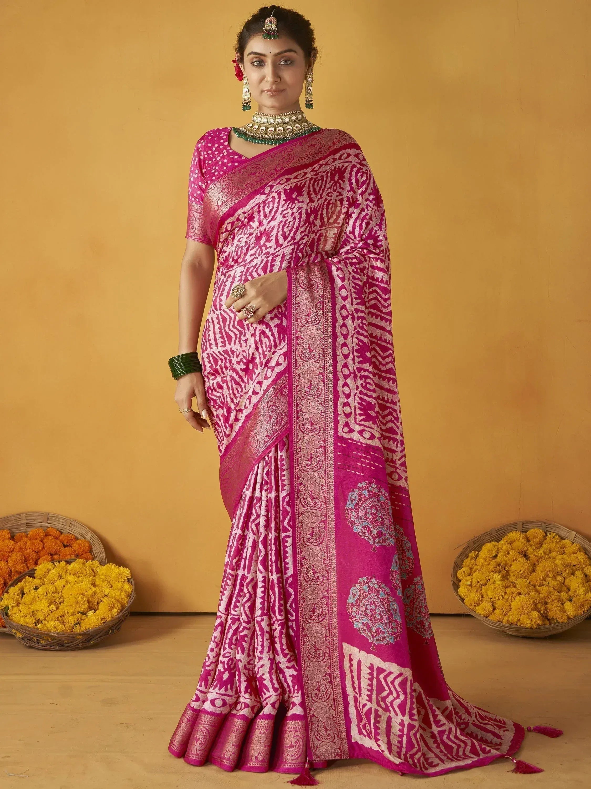 Pink and white printed saree with gold border, traditional Indian ethnic wear, paired with green jewelry and floral baskets