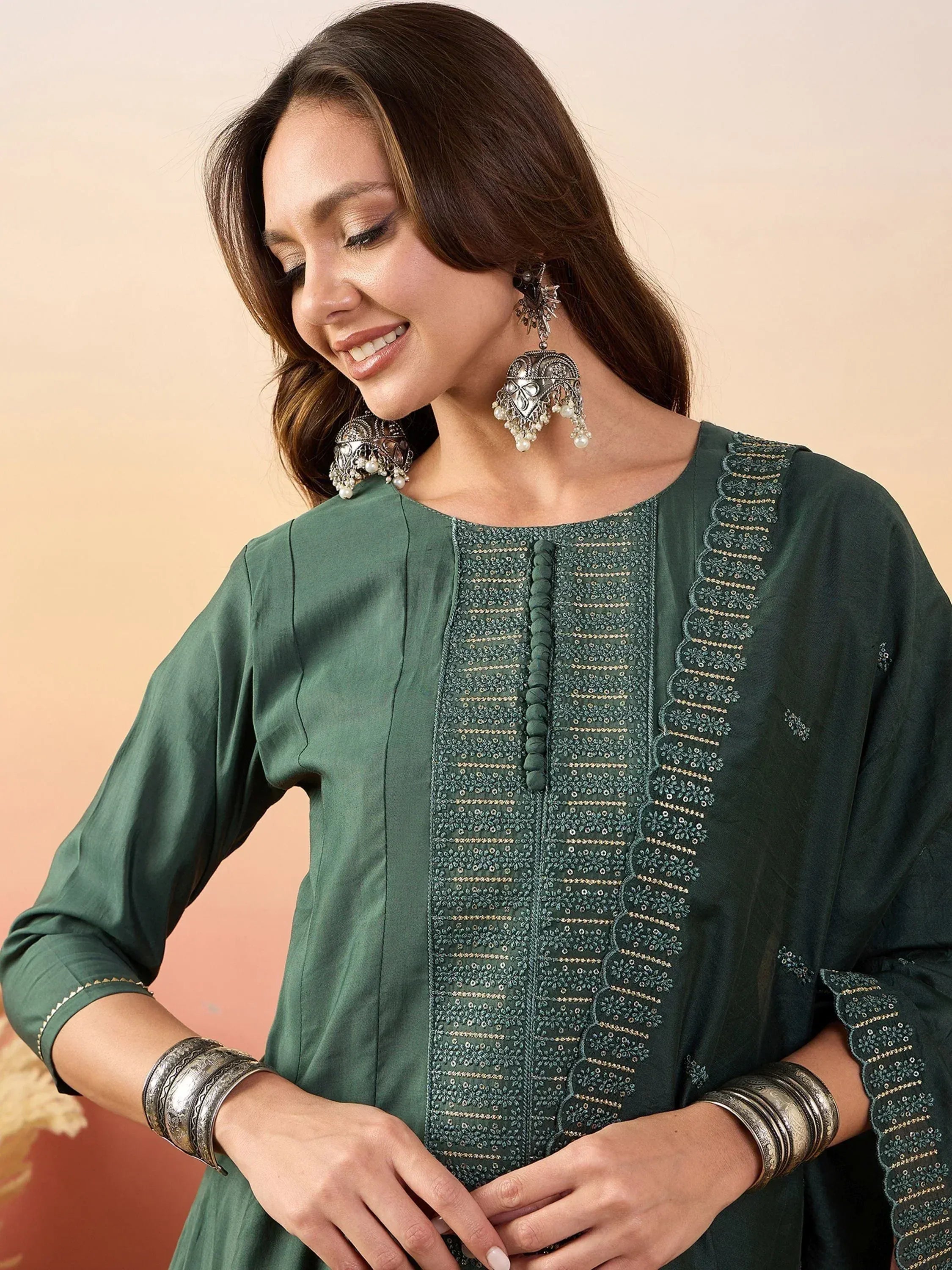 Woman in green embroidered ethnic kurta with pearl jhumka earrings and silver bangles