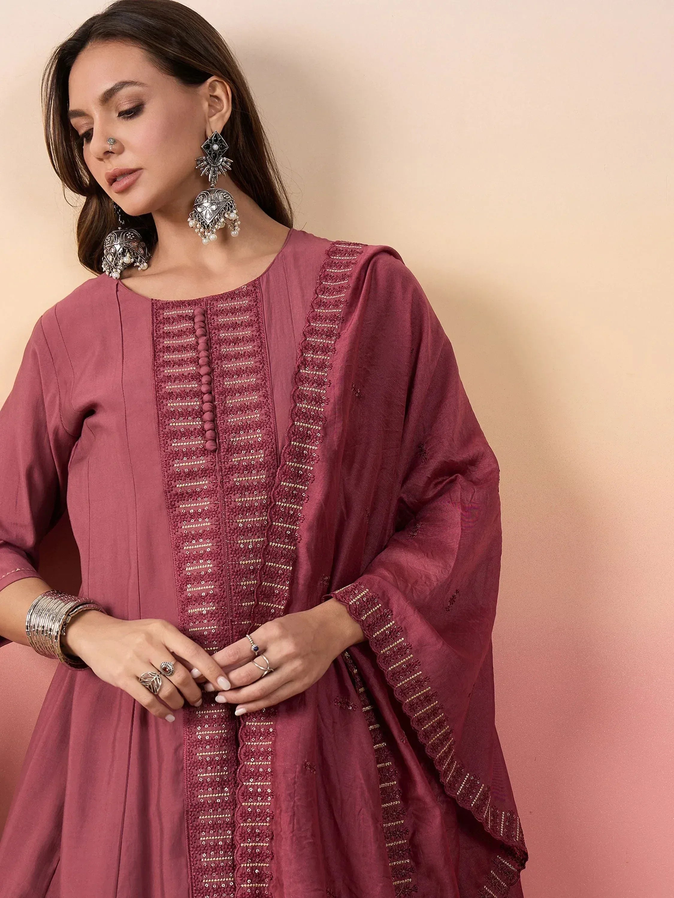 Woman in maroon ethnic kurta with embroidery, paired with statement earrings and bangles