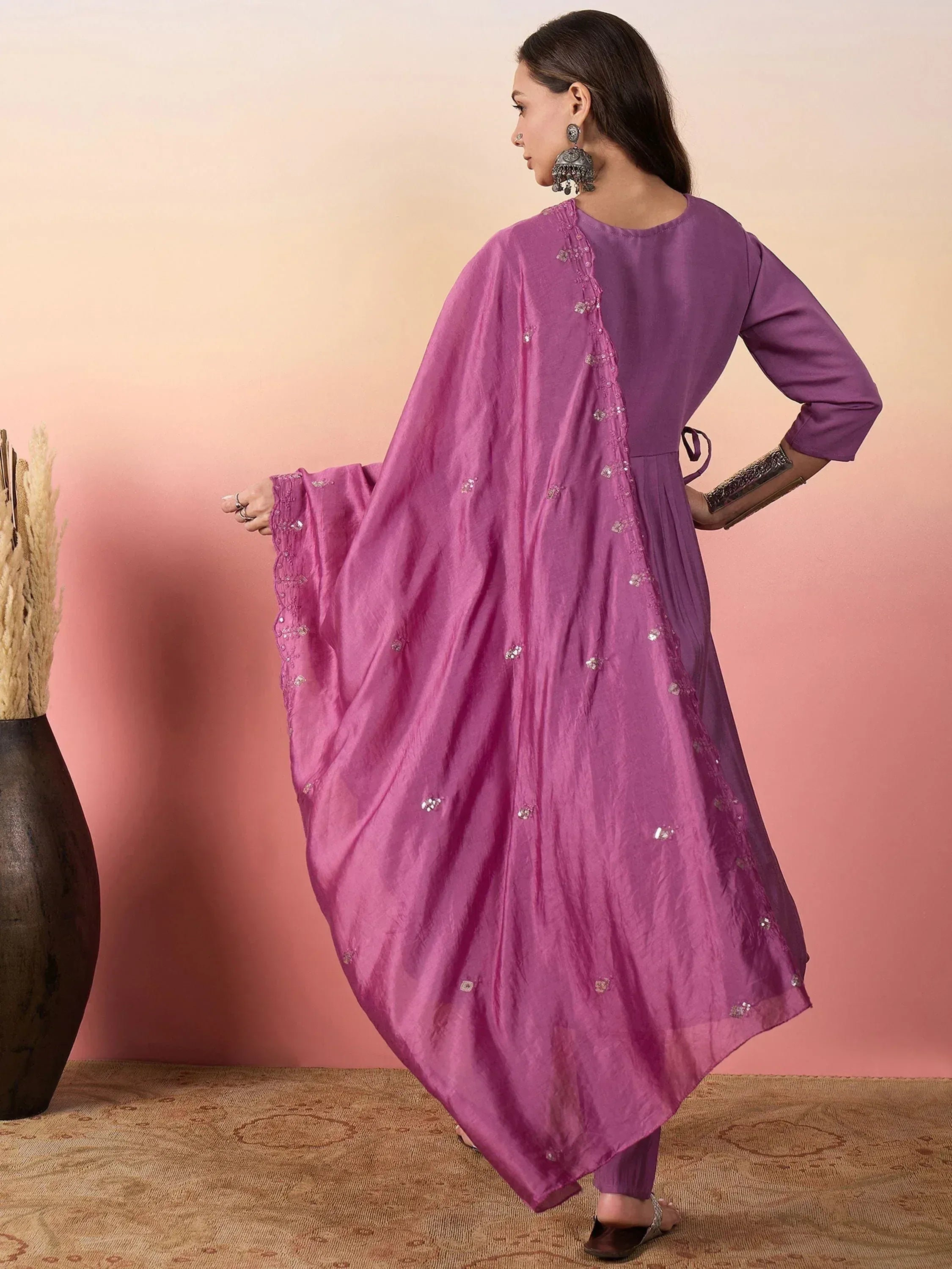 Purple ethnic gown with mirror work and cape sleeve, styled with traditional jewelry for Indian wear