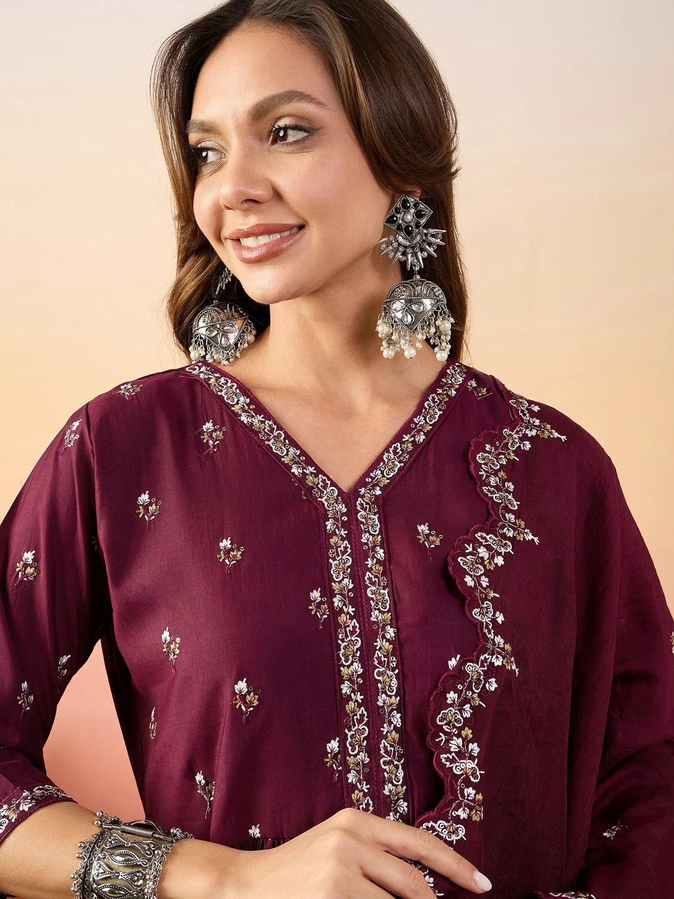 Woman in maroon embroidered ethnic kurta with floral detailing and statement earrings