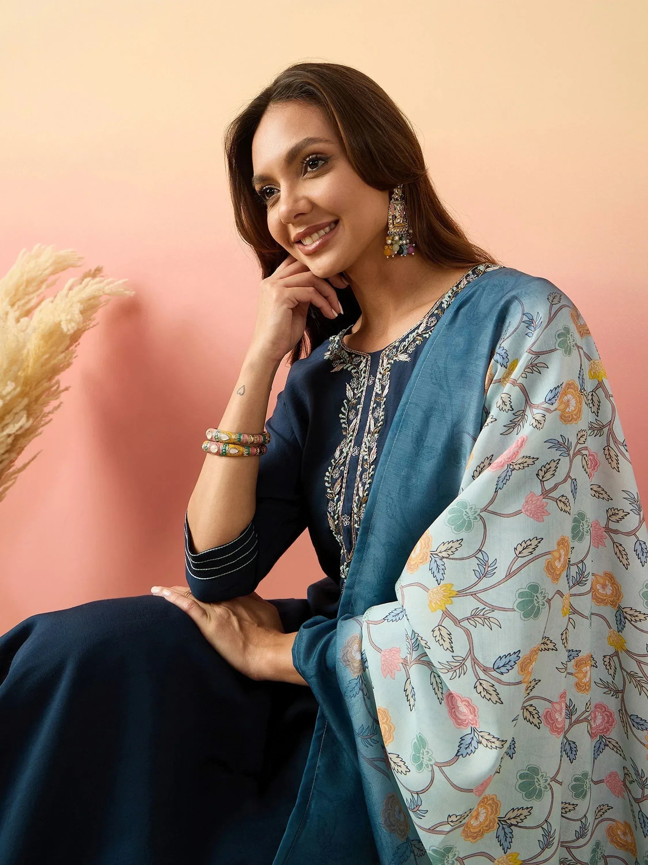 Woman in navy blue embroidered salwar kameez with floral dupatta, styled with colorful bangles and earrings