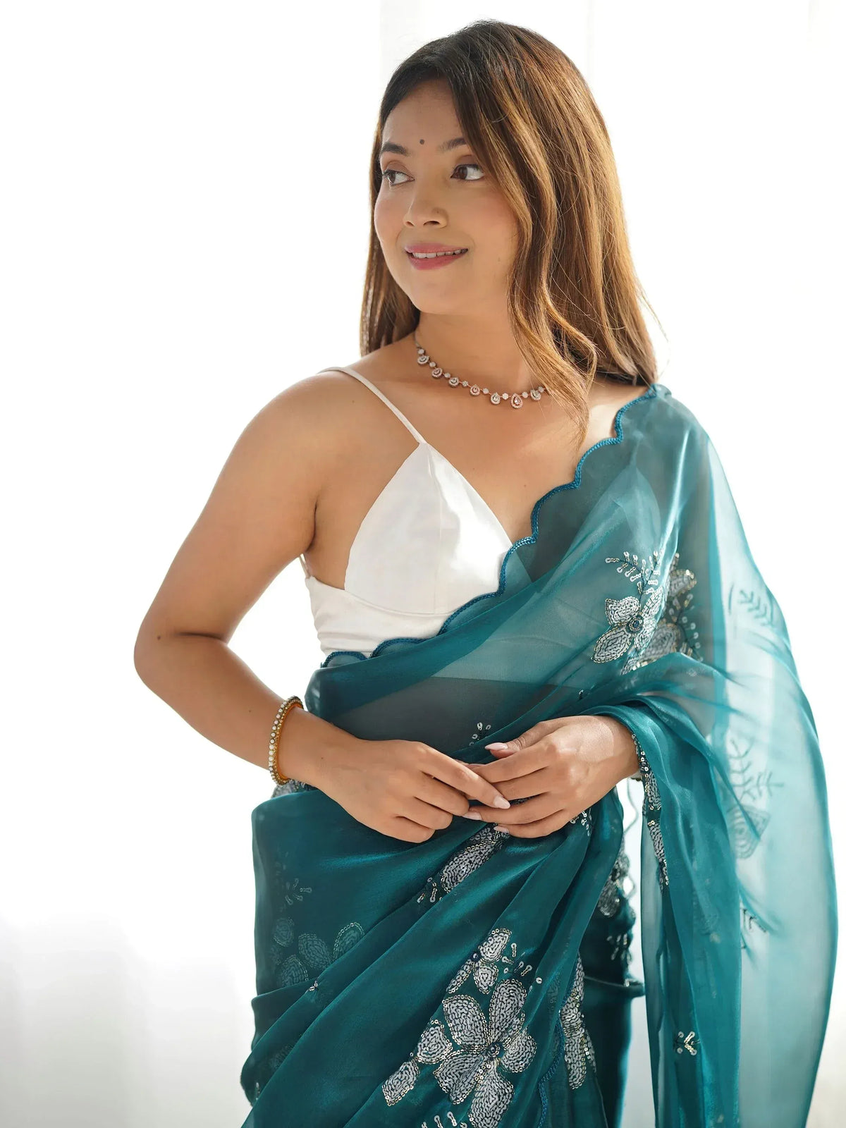 Woman in teal embroidered saree with white blouse, floral sequin details, perfect for Indian ethnic wear occasions.