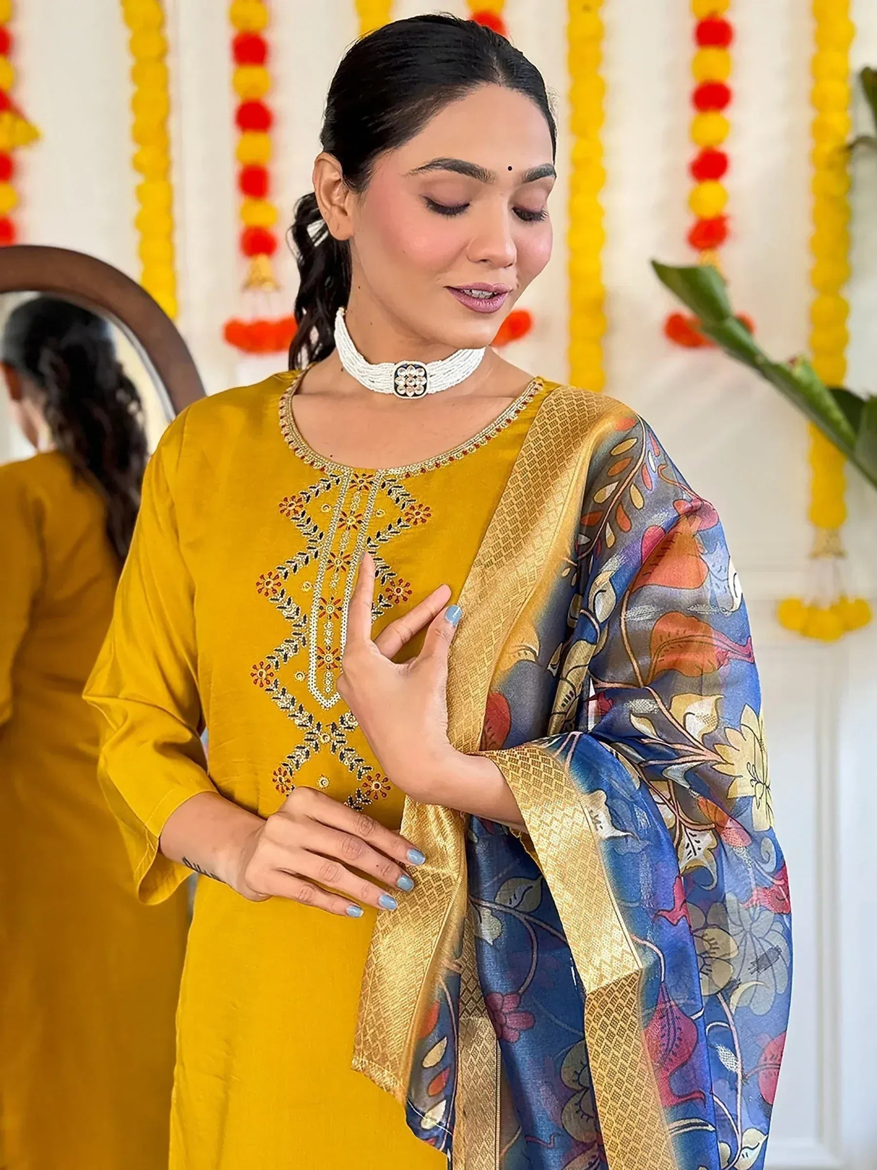 Woman in mustard yellow embroidered kurta with floral dupatta, festive Indian ethnic wear