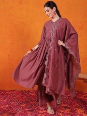 Woman in mauve embroidered ethnic gown from Ethnic Plus, posing on rose petals with orange wall
