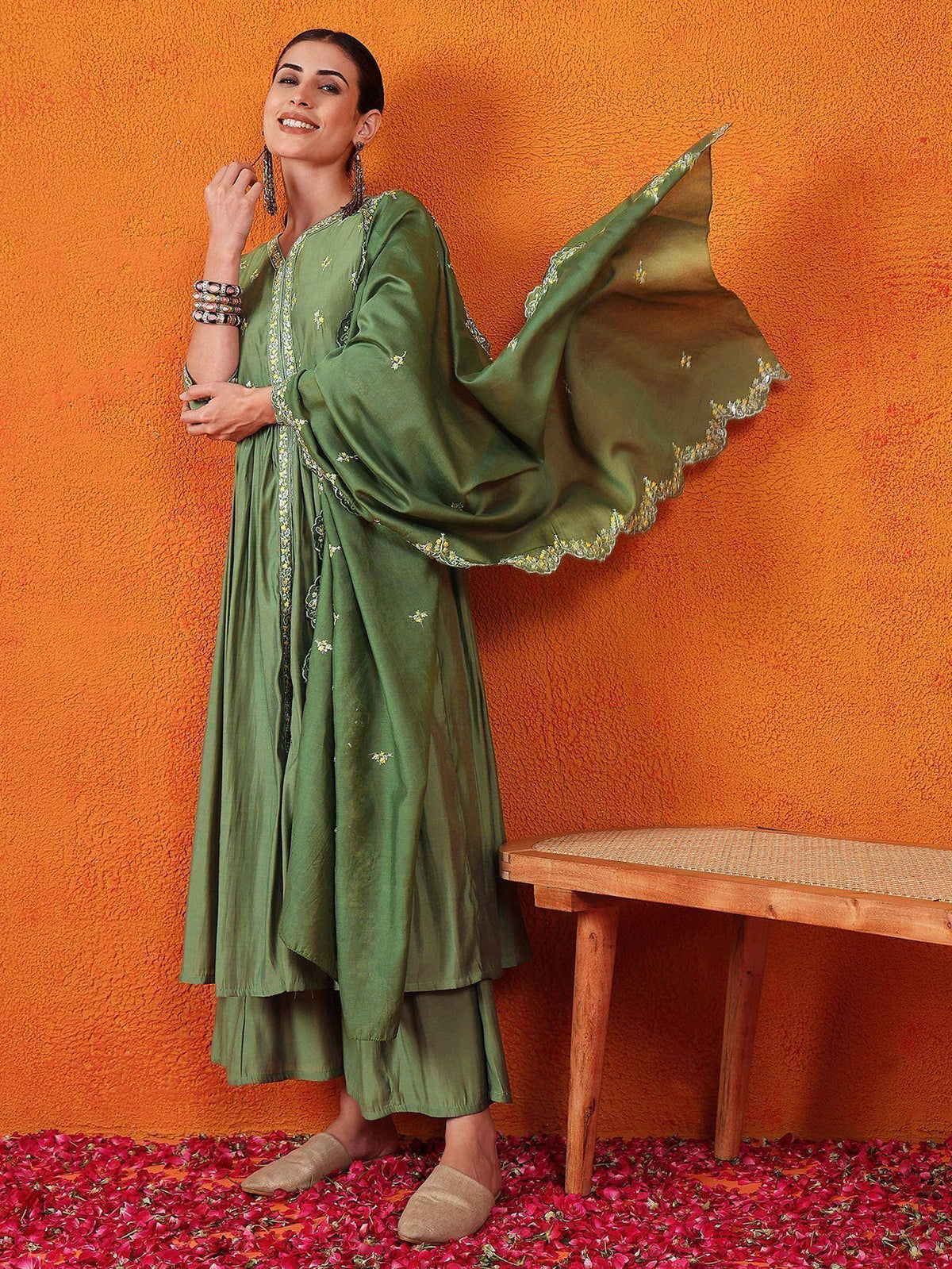 Olive green embroidered ethnic kurta with flared sleeves and matching palazzo, styled with rose petals and wooden bench