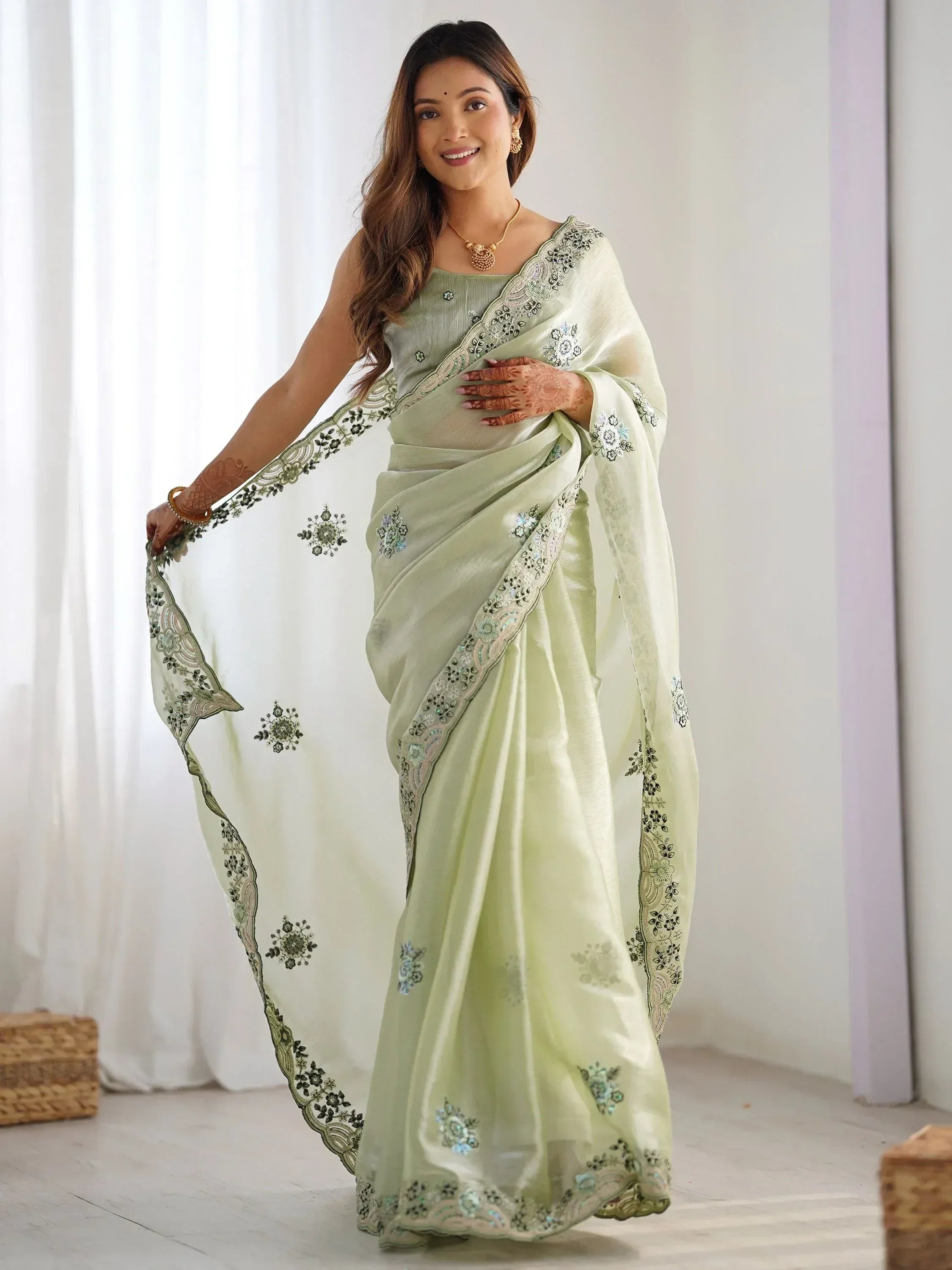 Woman in elegant light green embroidered saree with floral detailing, perfect for Indian ethnic occasions.