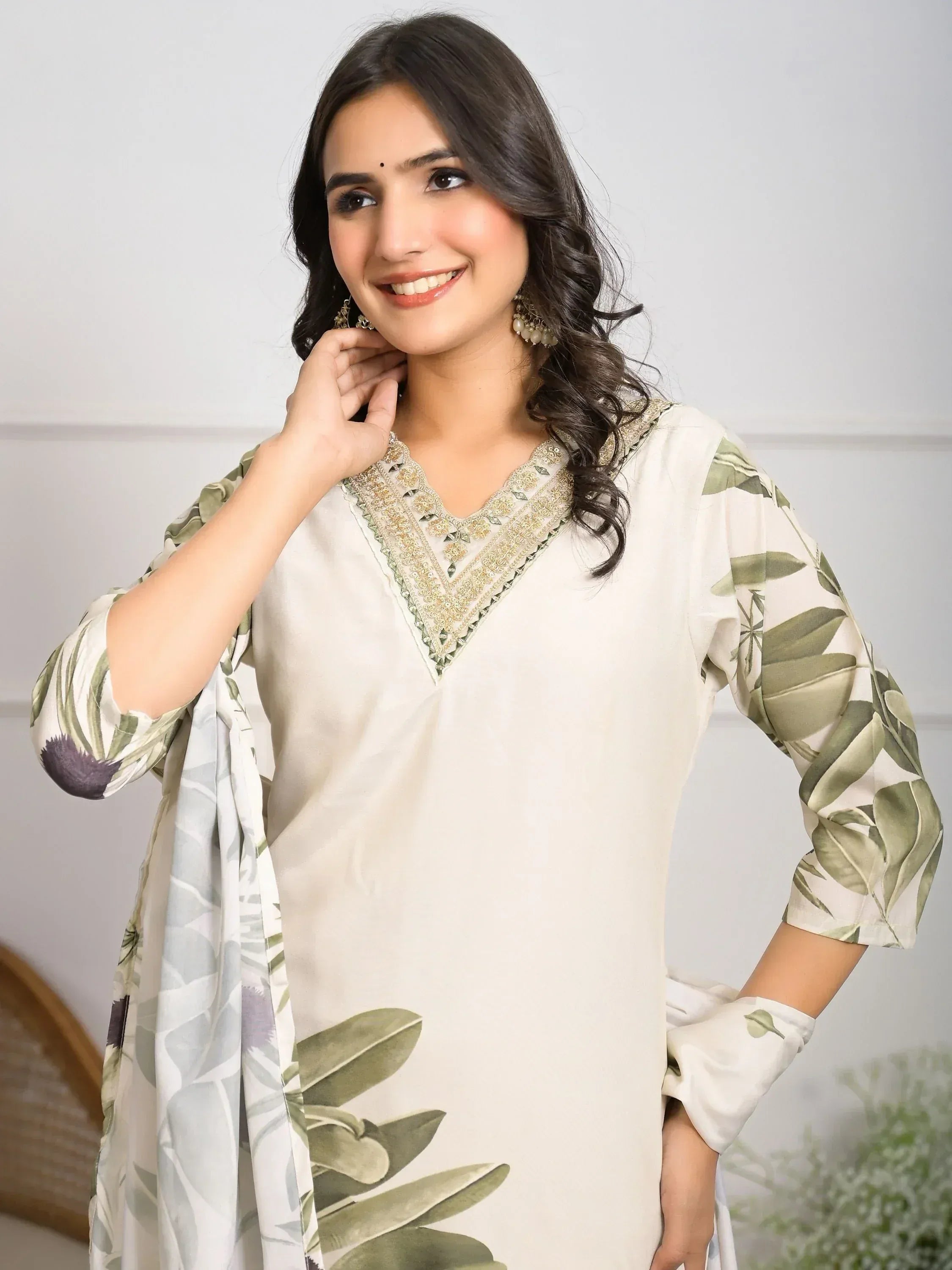 Woman in elegant cream salwar kameez with green leaf print and gold embroidery, perfect for Indian ethnic wear.