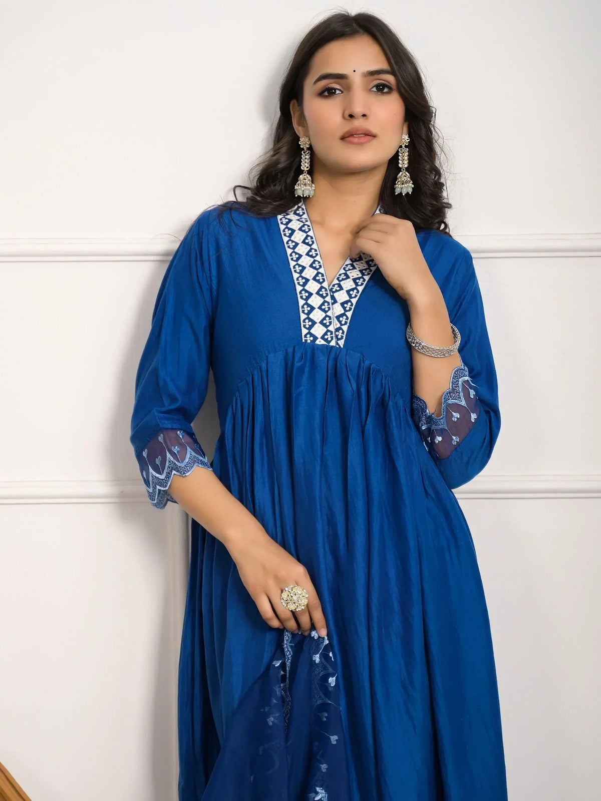 Royal blue ethnic gown with white geometric neckline embroidery and sheer lace sleeves, styled with jhumka earrings.