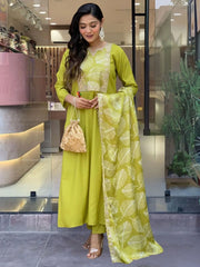 Woman in light green ethnic suit and dupatta, holding golden potli bag, standing outside boutique