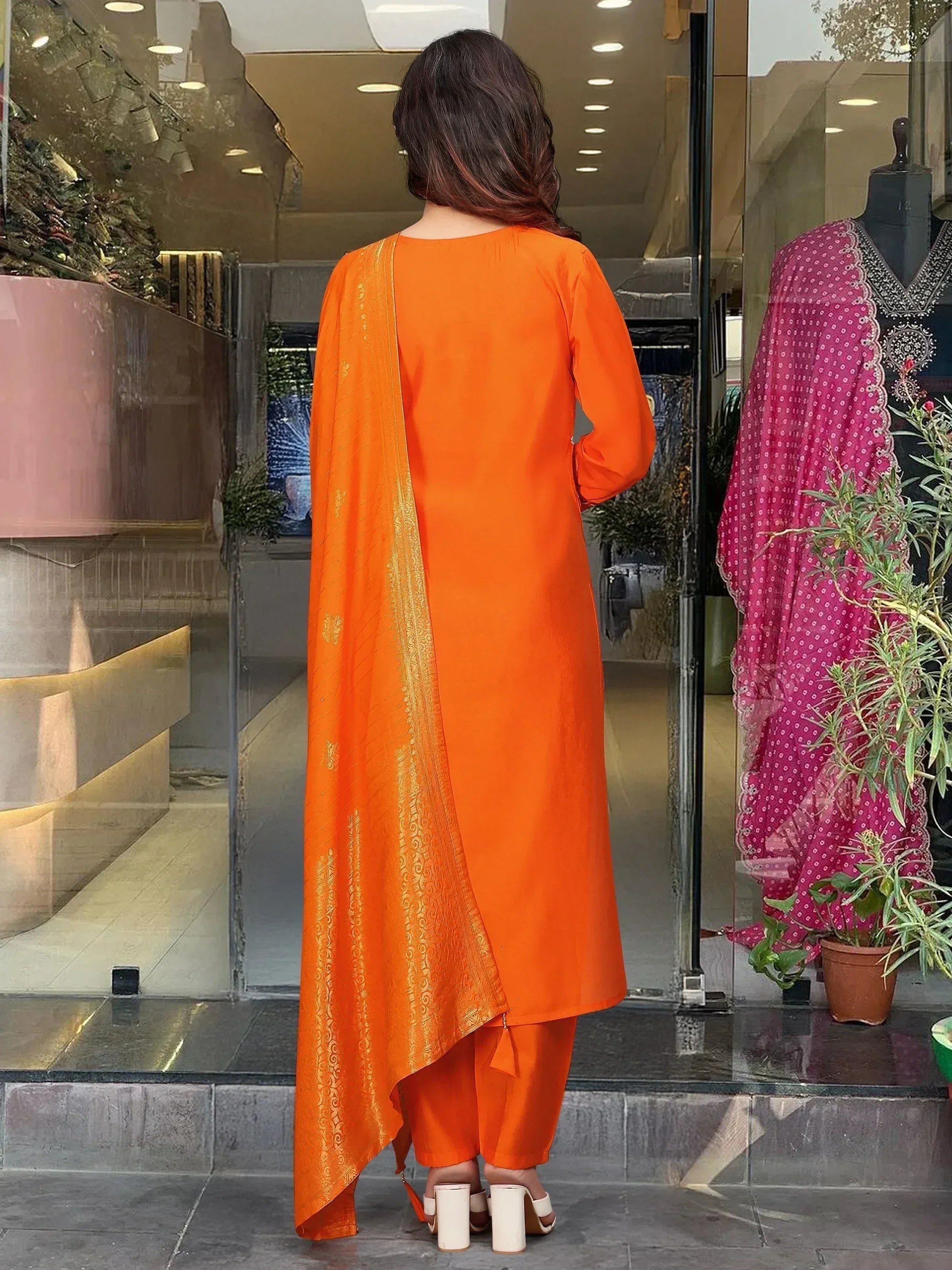 Vibrant orange ethnic kurta with gold detailing, paired with matching pants and dupatta, perfect for festive occasions.